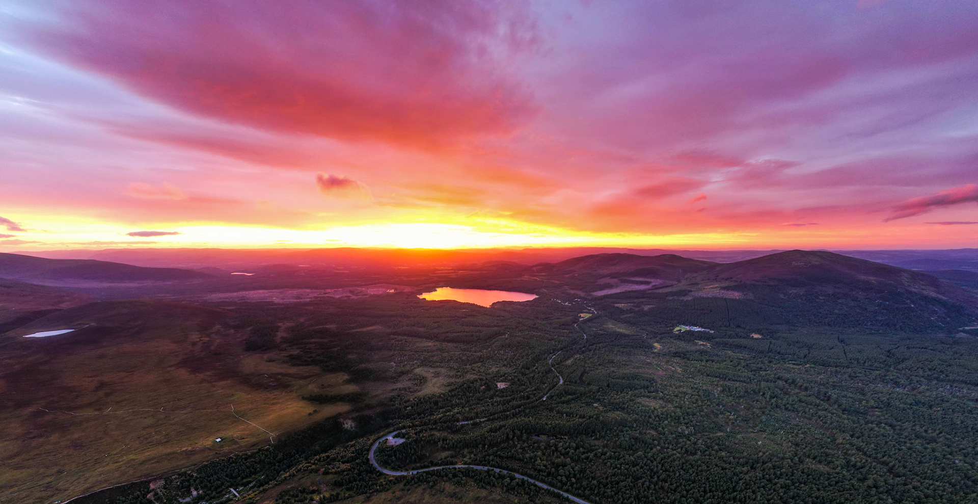 Bright red sunset over the Cairngorms National Park looking towards Aviemore and Loch Morlich in Scotland. From above.