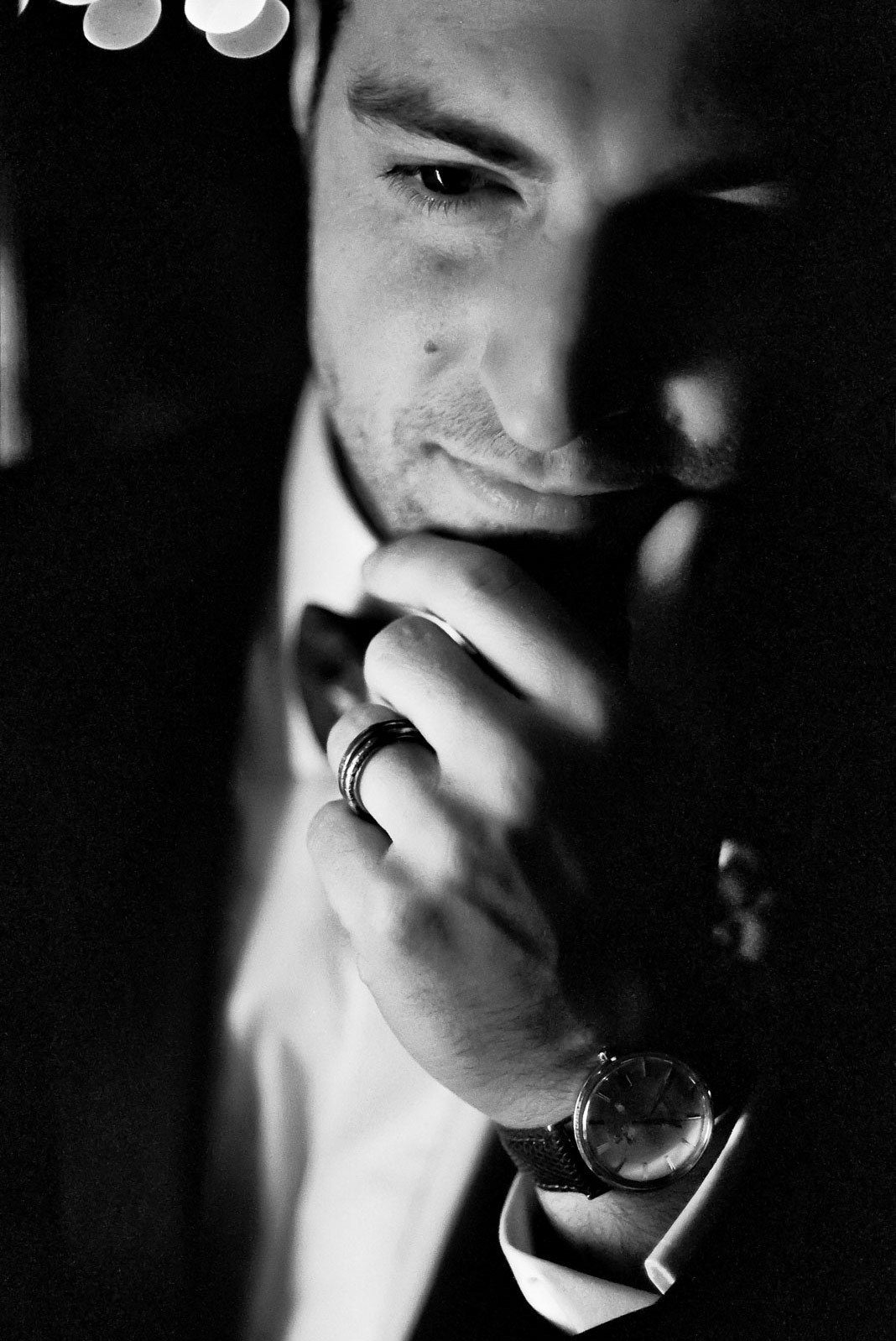 Soft close-up of groom's face and hands with wedding ring