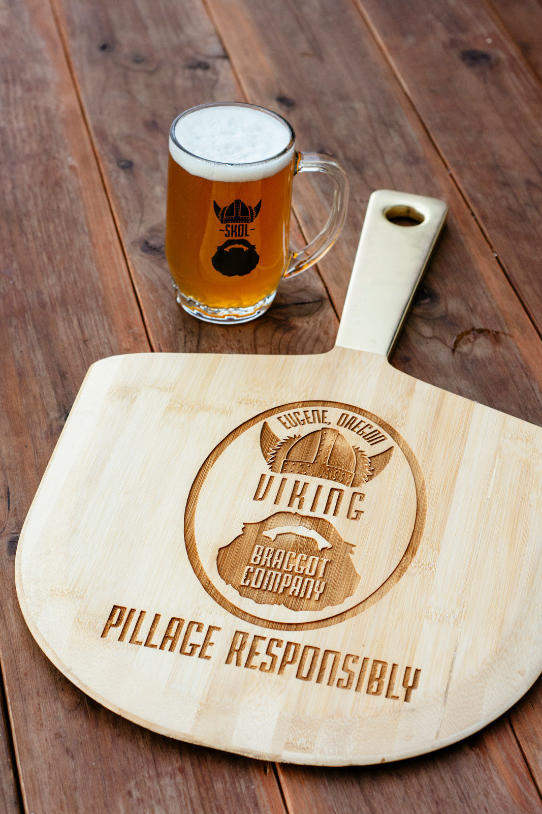 Pizza oven paddle with Viking logo engraved placed next to pint of beer