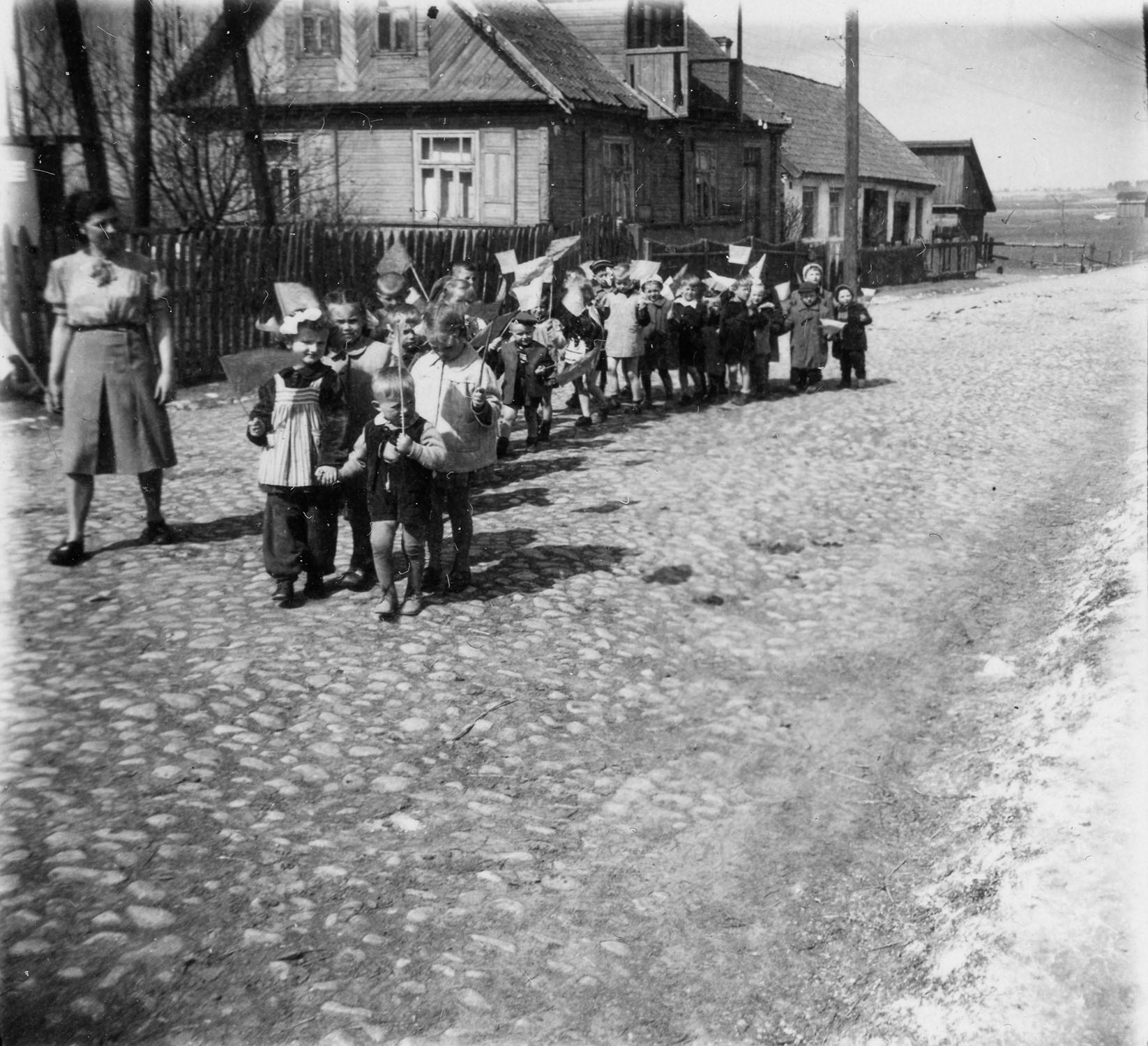 Lata 50. XX wieku (I. poł.) | Uroczystość 1-majowa - dzieci z chorągiewkami na ul. 11-go Listopada (obecnie ul. Grzegorza Chodkiewicza) | z arch. Zespołu Szkolno-Przedszkolnego w Zabłudowie