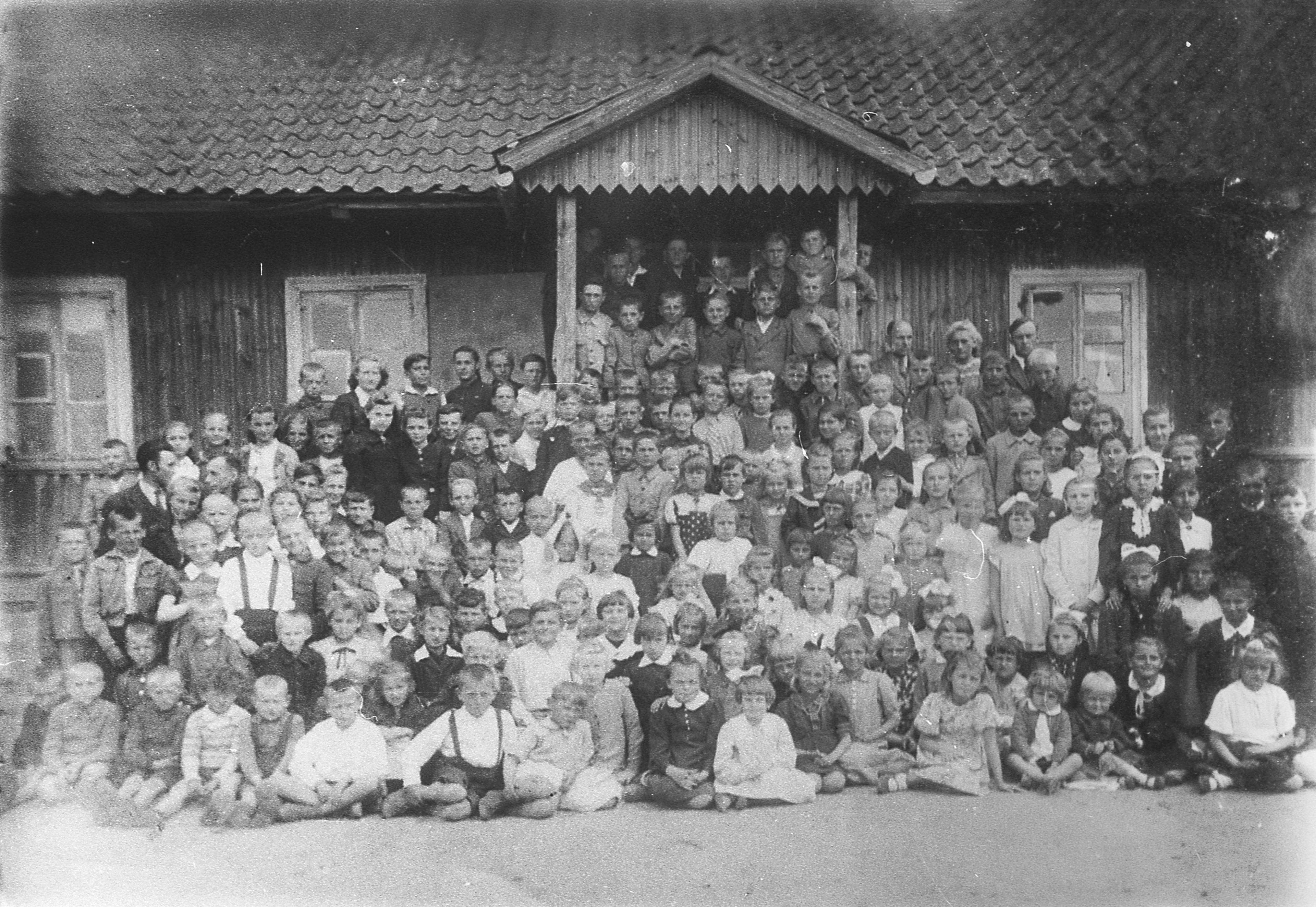ok. 1945 | Grono pedagogiczne i uczniowie przed Publiczną Szkołą Powszechną w Zabłudowie przy ul. Adama Mickiewicza - 2. od prawej u dołu Stanisława Sacharewicz z d. Powichrowska / w drugim rzędzie za chłopcem z szelkami w białej koszuli Jan Powichrowski | z arch. MOAK