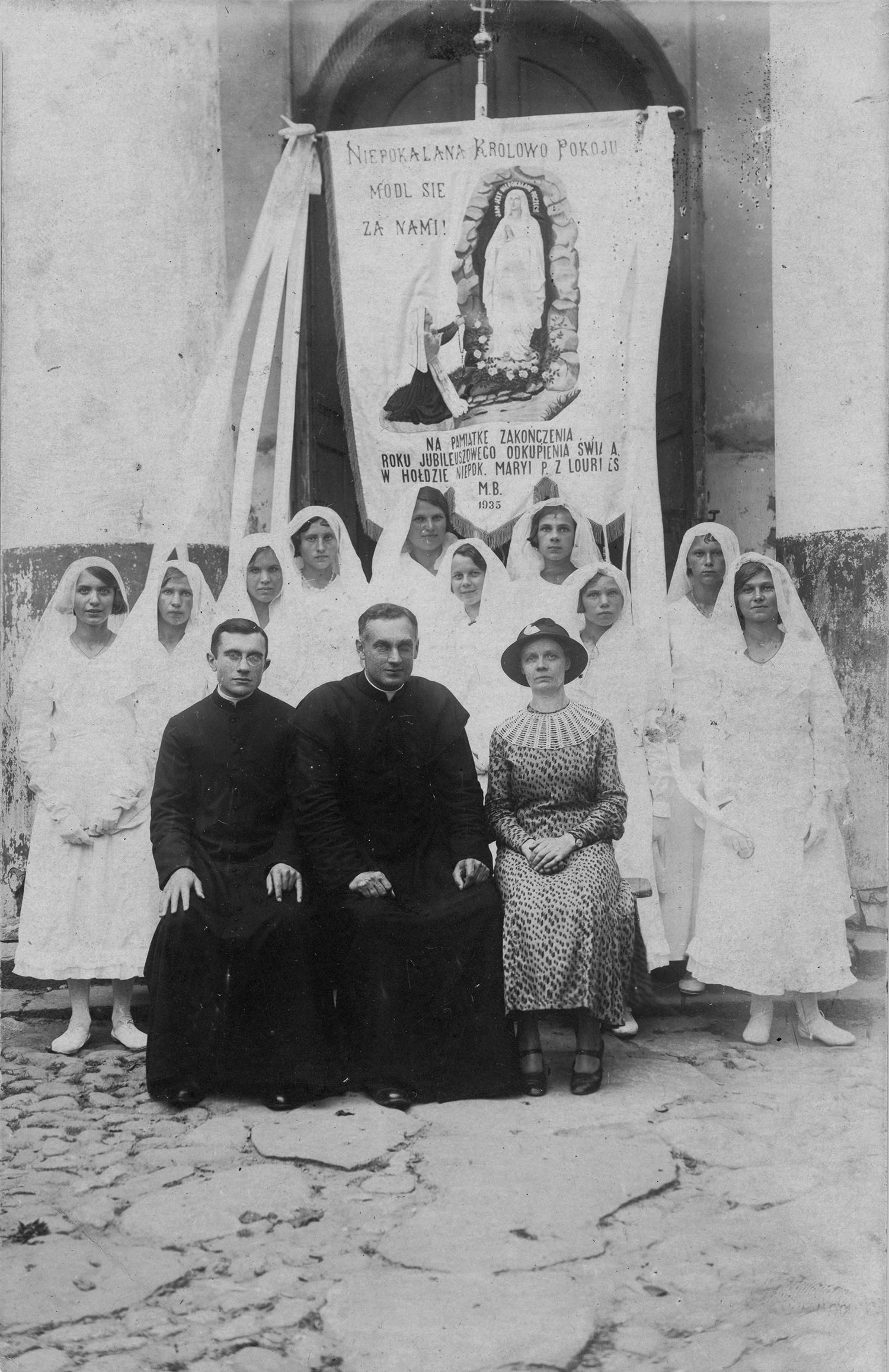 1935 | Grupa kobiet z Folwarków Małych i Folwarków Wielkich po procesji Bożego Ciała - siedzą od lewej: ks. Adolf Jaroszko(?), ks. proboszcz Witold Kuźmicki, Jadwiga Jaroszewicz z d. Dąbrowska (żona Michała - właściciela dworku w Rafałówce, posła na Sejm II RP w latach 1930-1935) | z arch. Agnieszki Dudzińskiej