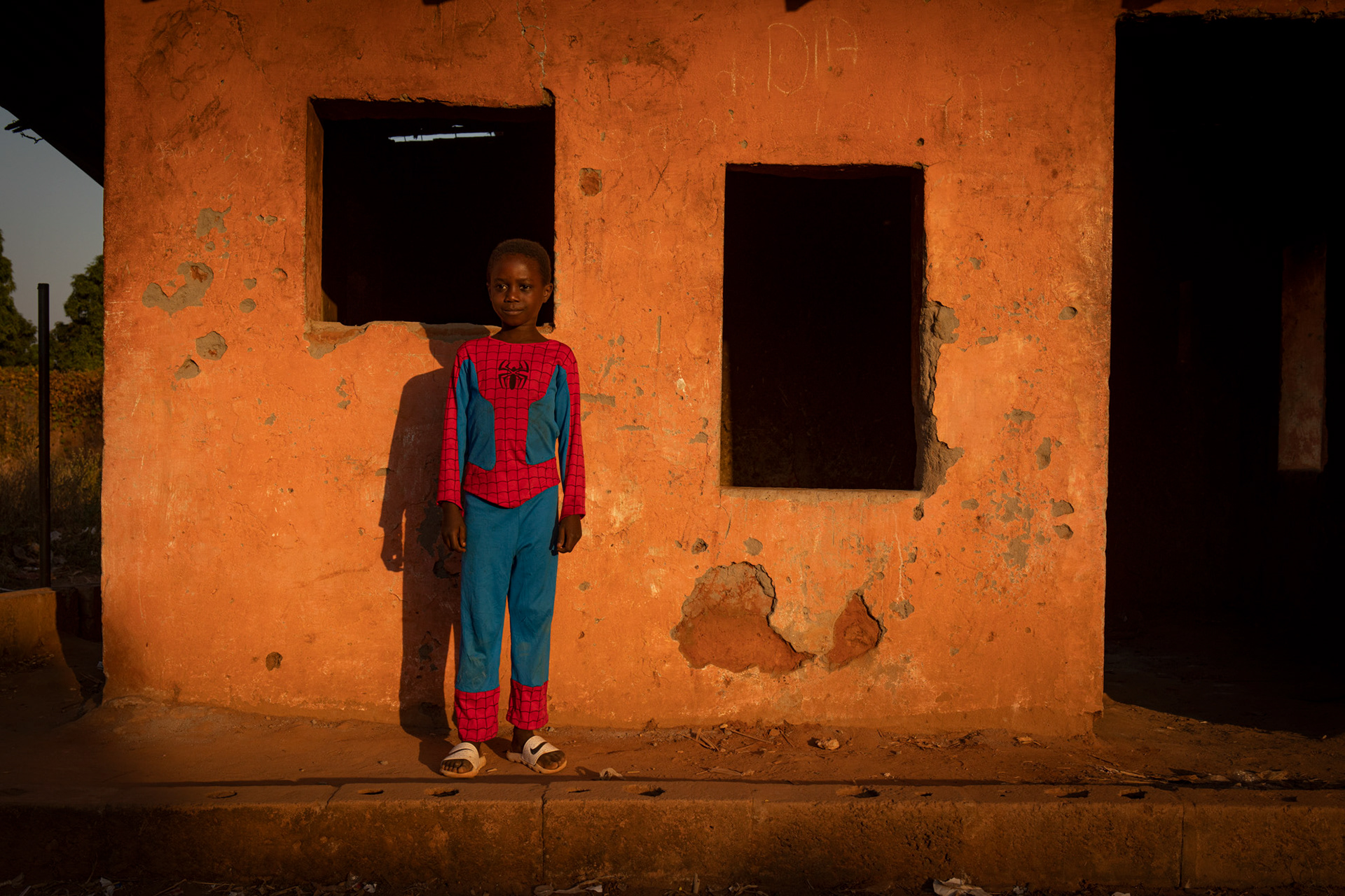 little kid dressed like superman in nhacra teda, guinea bissau, africa. Bambino vestito da superman nel villaggio di nhacra teda, guinea bissau, africa