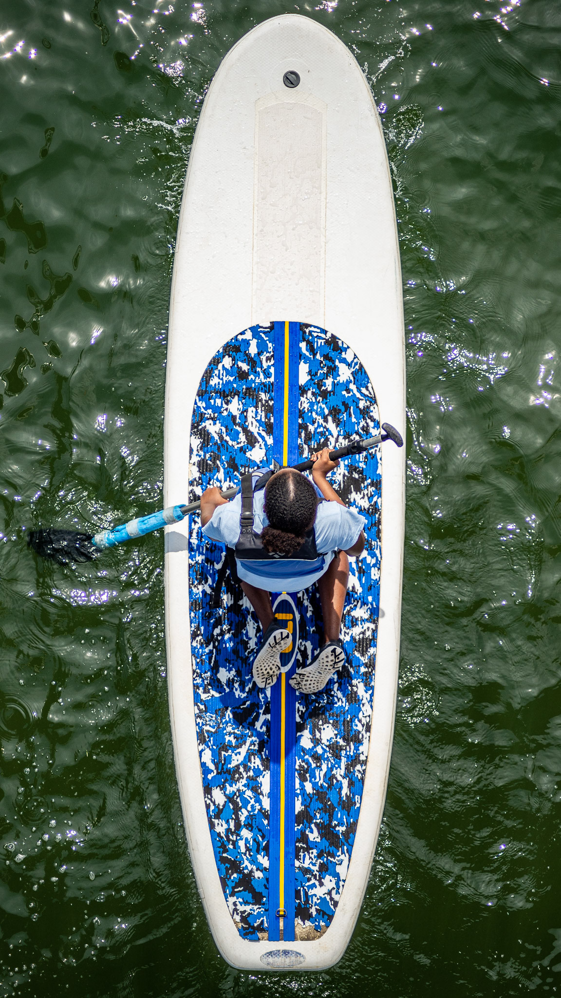 A camper paddle boards in the Boston harbor at Camp Harbor View.