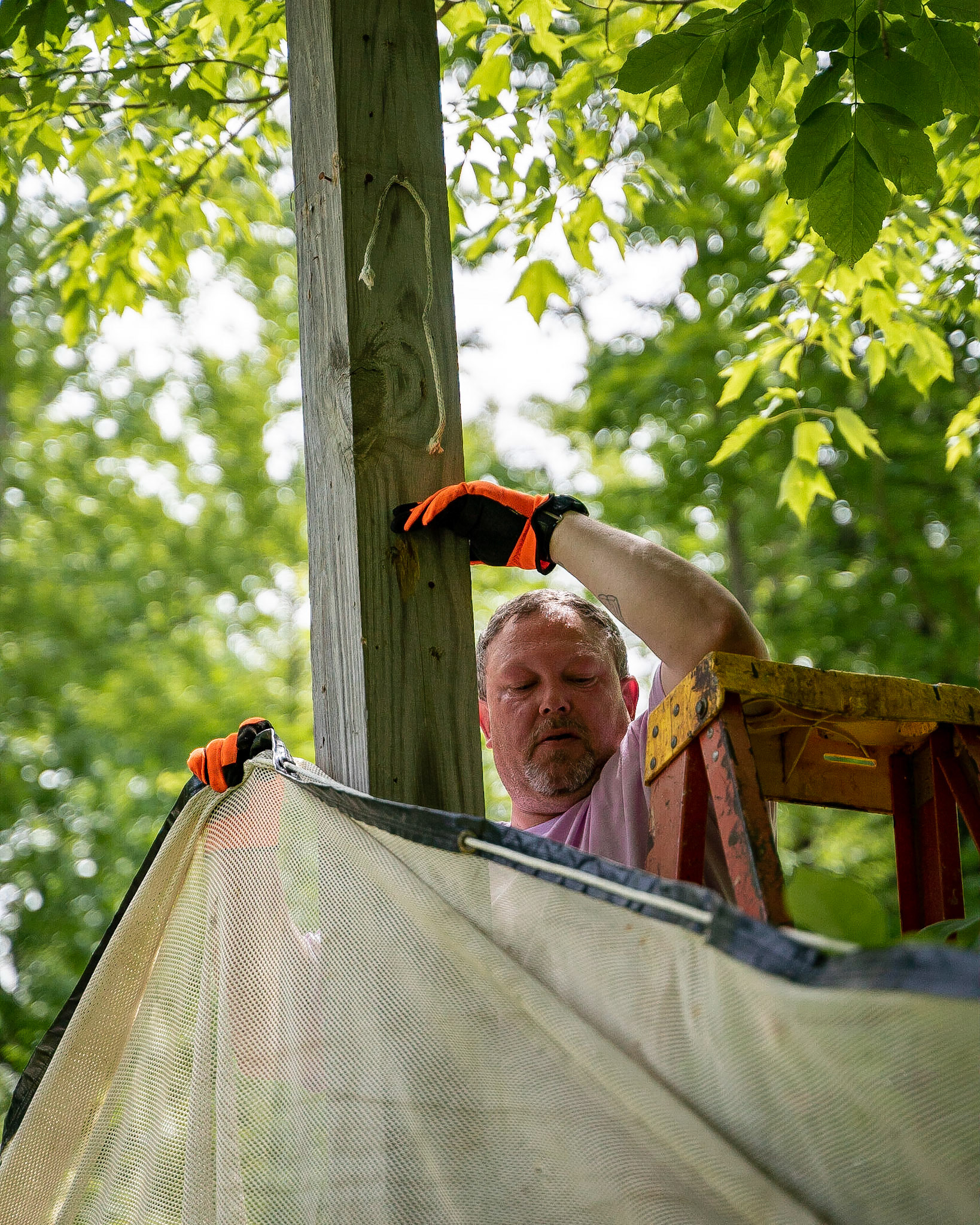 Camp Emerson Wilderness Director Ron sets up netting at the end of the archery course to prevent arrows from disappearing into the woods during staff training week.