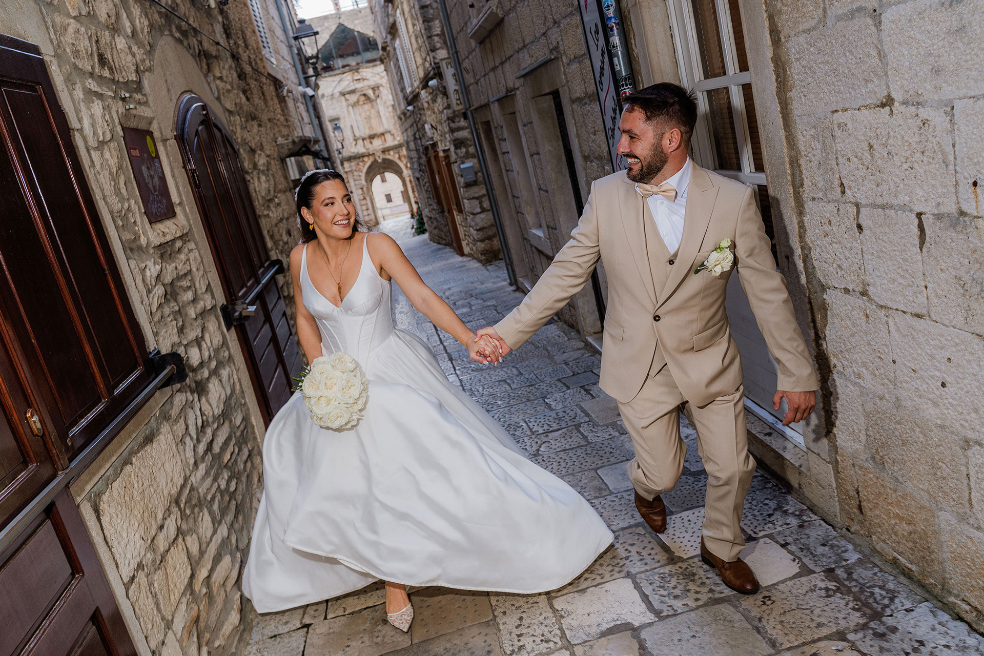 Bride and groom walking through stone streets of Korčula old town