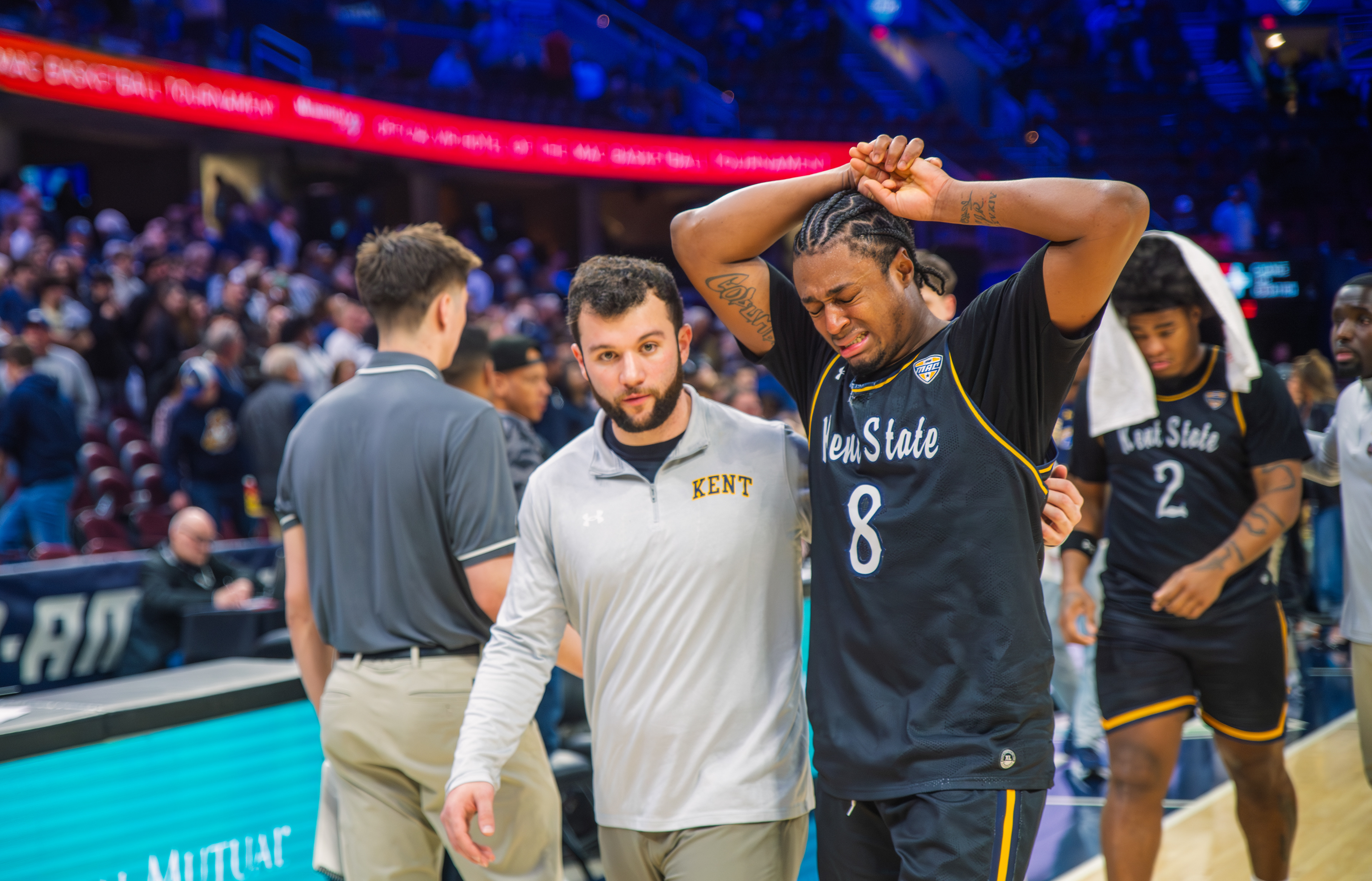 The final buzzer lands like a weight — a Kent State guard is consoled by a staff member after the Flashes' MAC Tournament run comes to an end at Rocket Mortgage FieldHouse.