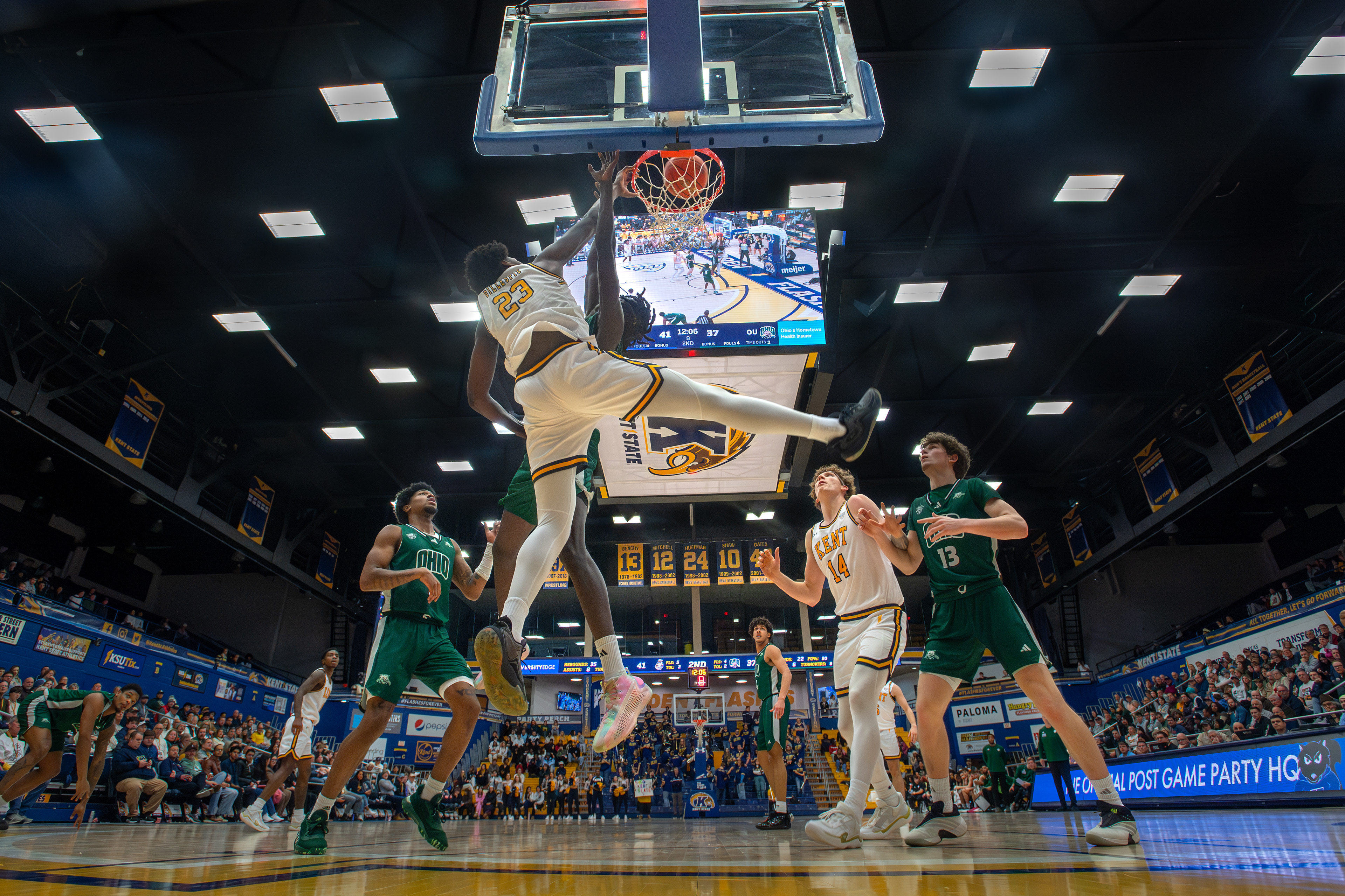 A Kent State center finishes through contact at the rim as the crowd fills every corner of the MACC. Captured from beneath the basket with a remote camera.