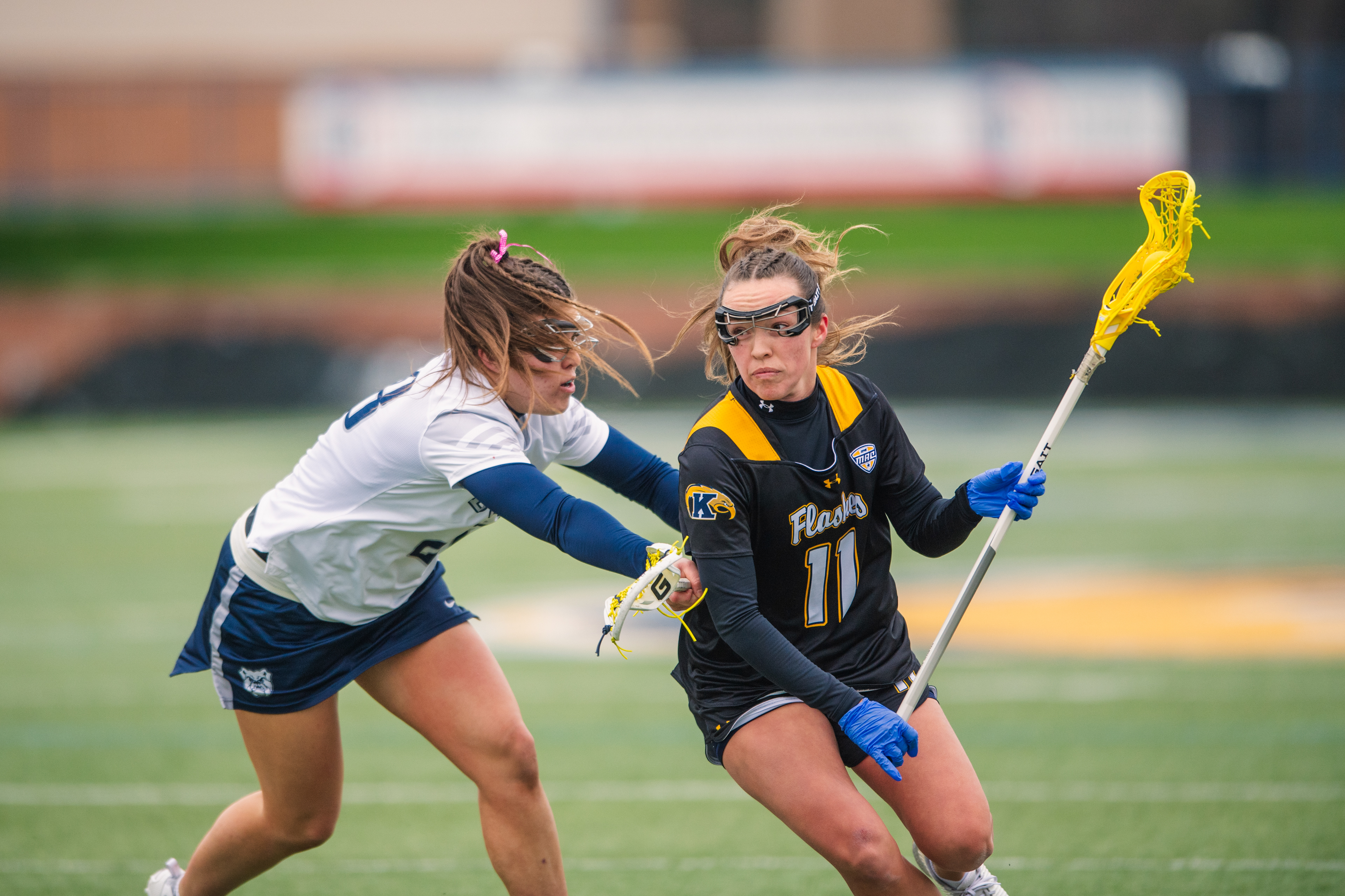 Kent State's #11 sets her jaw and drives the edge against a Butler defender. The determination in her face says everything about what the possession is worth.