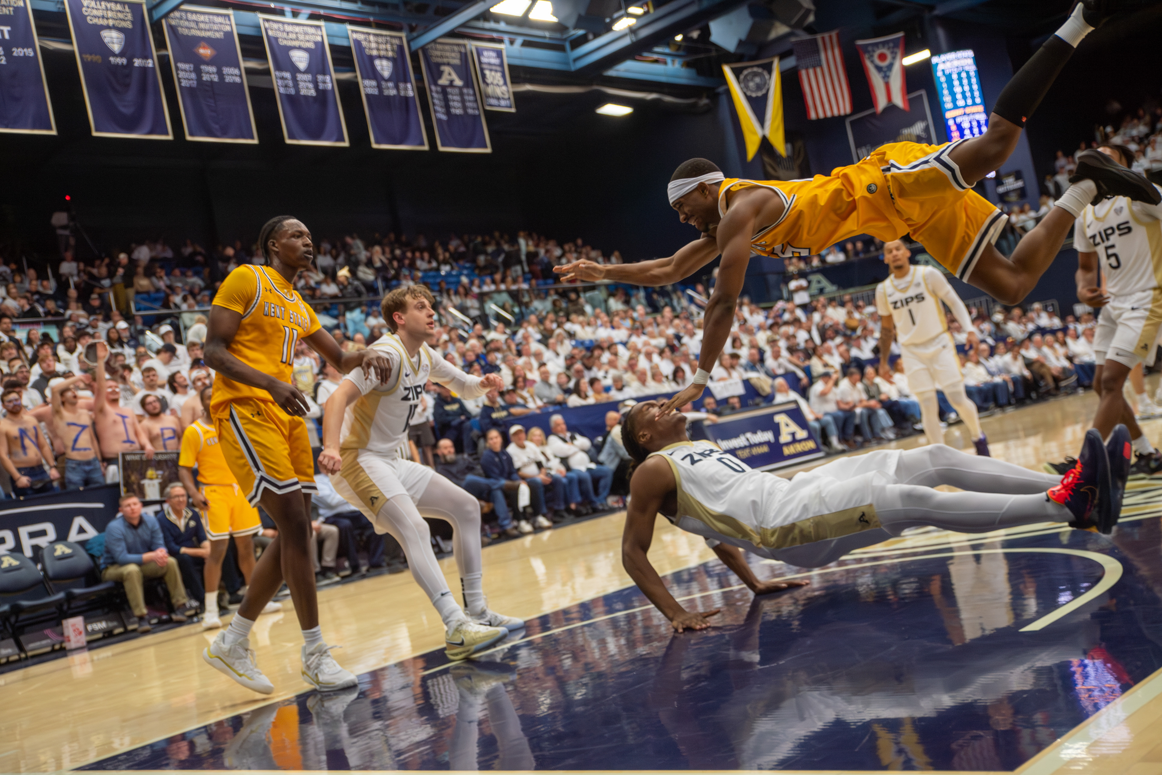 A Kent State guard goes horizontal diving for a loose ball in front of the Akron student section, giving everything for possession in a rivalry road game.