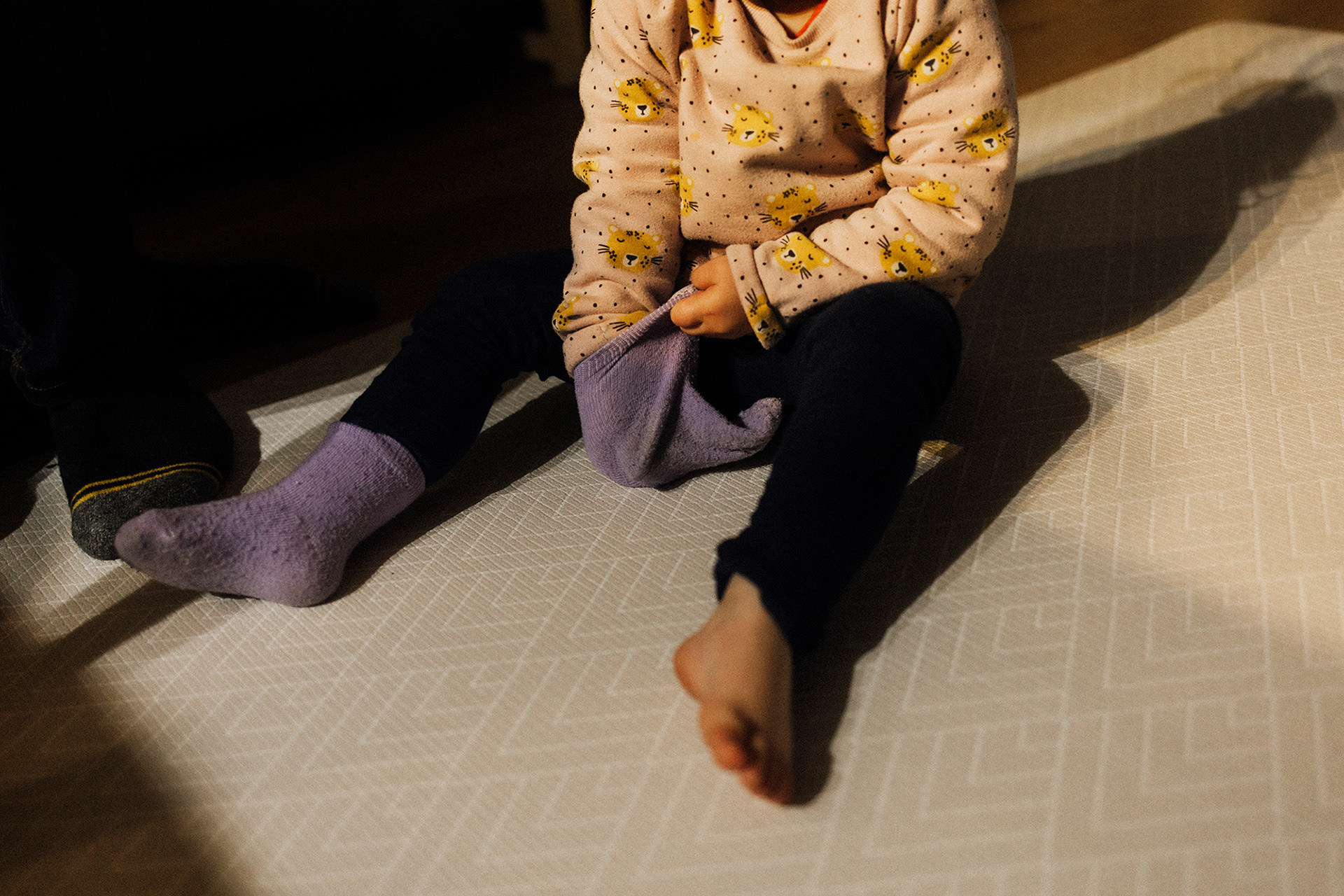 girl putting purple socks on her hands