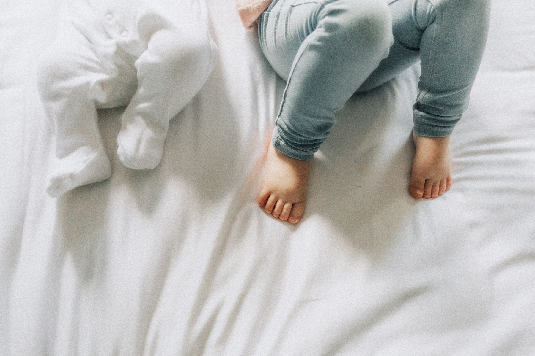 big sister's fet next to baby brother's feet