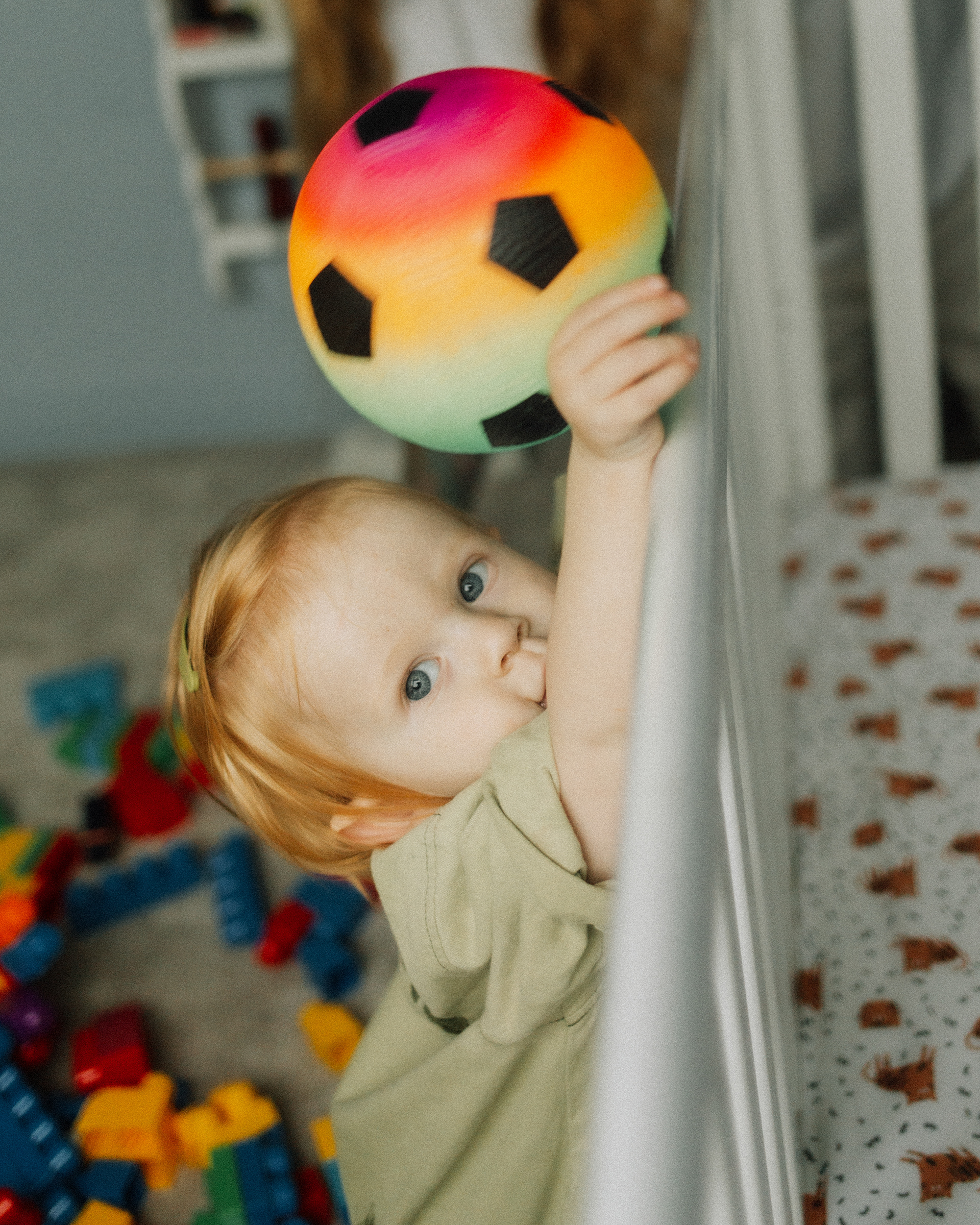 boy leaning on cot with colourful ball
