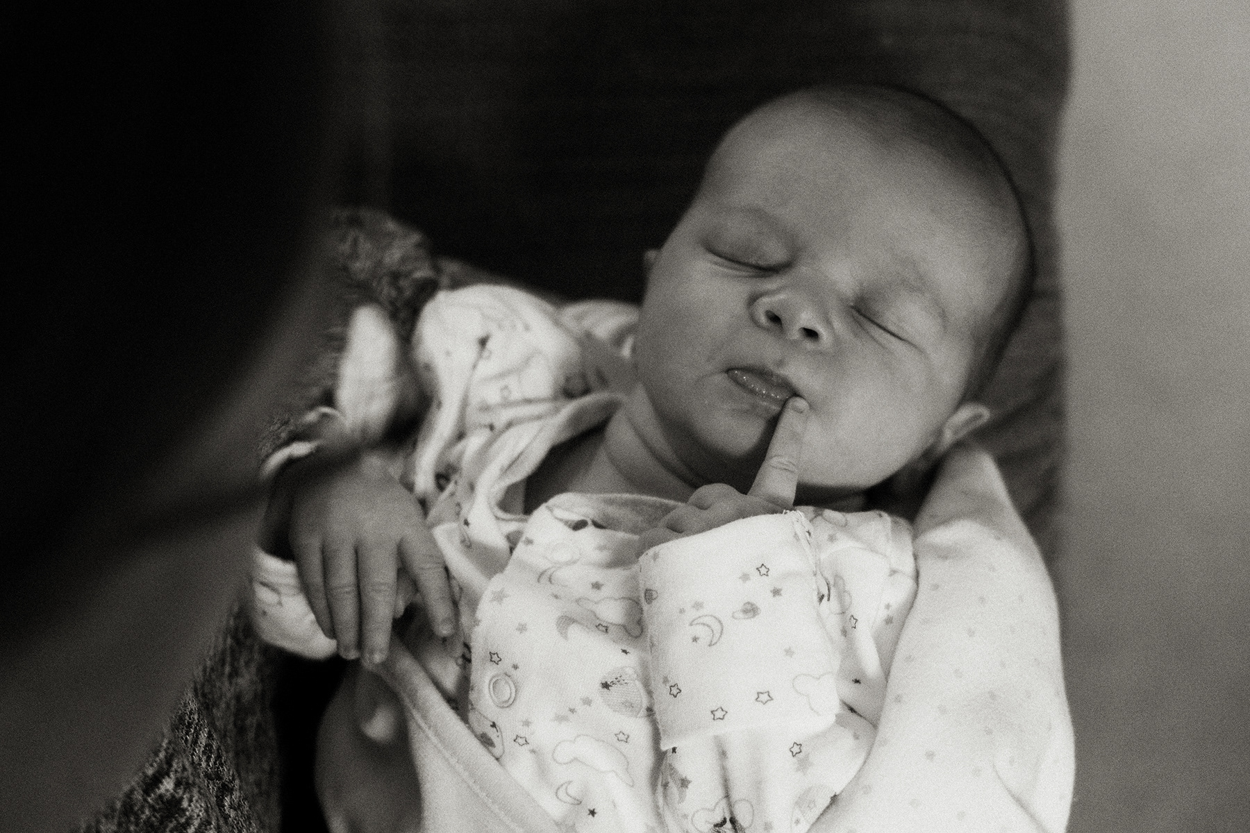 newborn baby with index finger held up to his mouth
