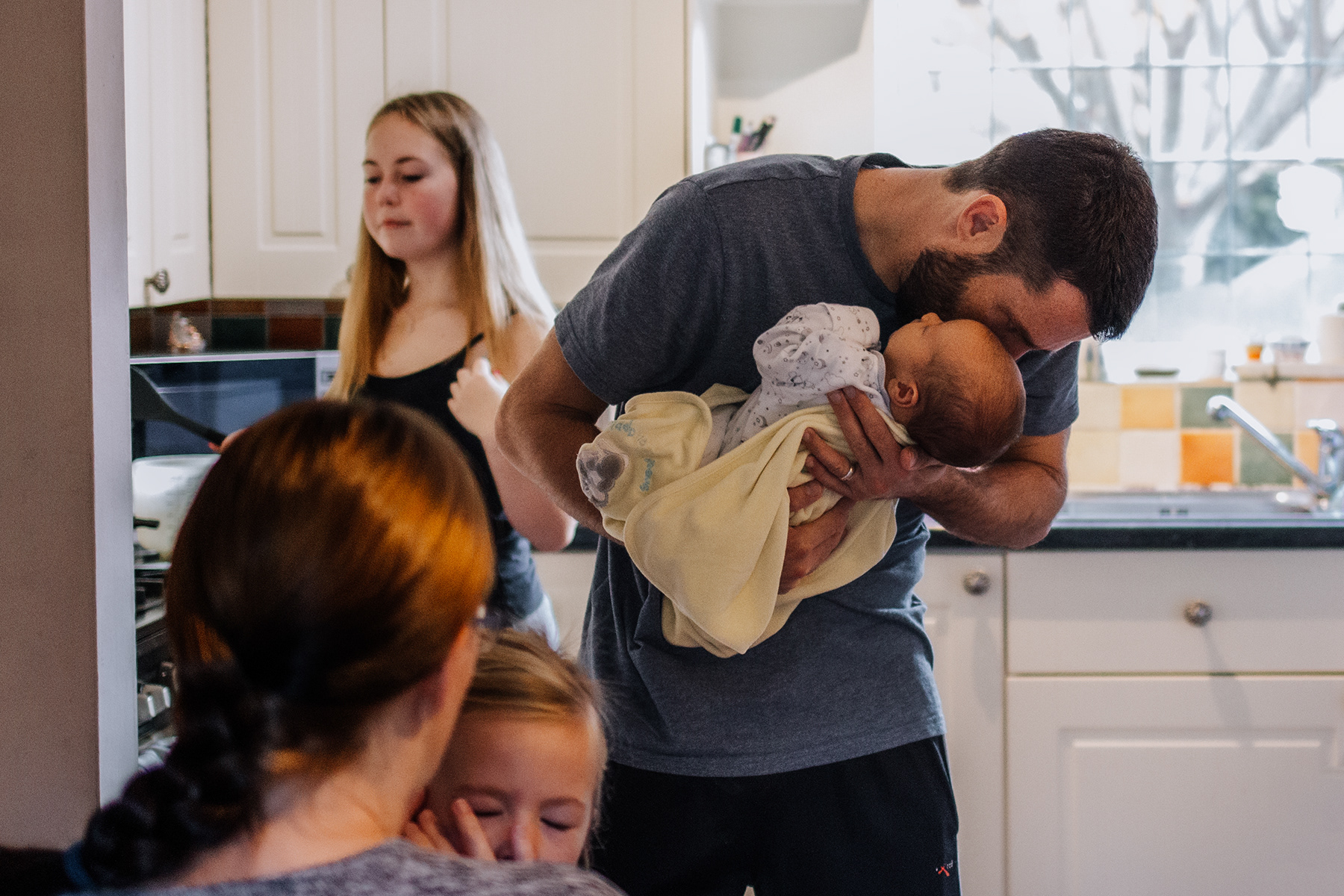 father kissing newborn baby