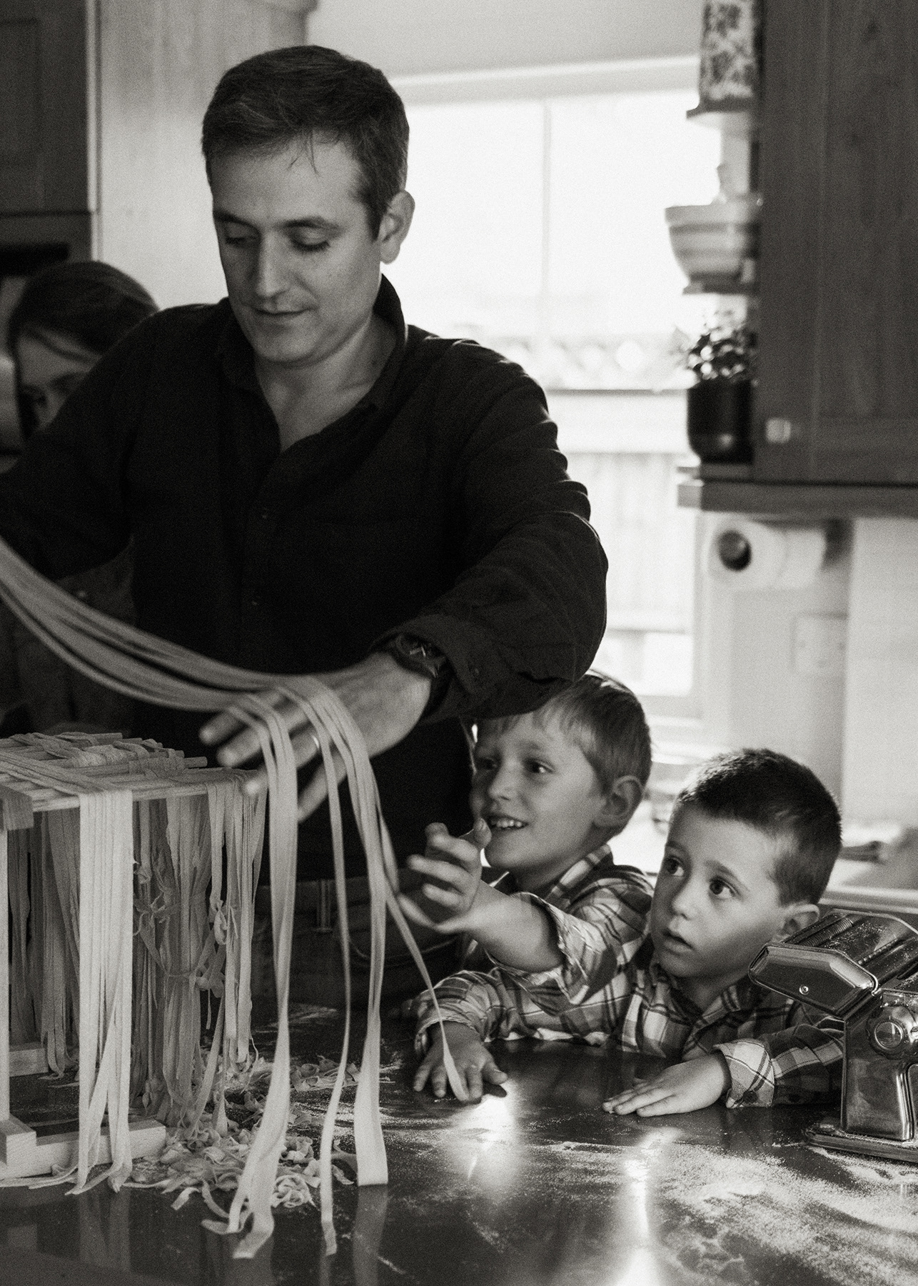 little boys watching father hang pasta