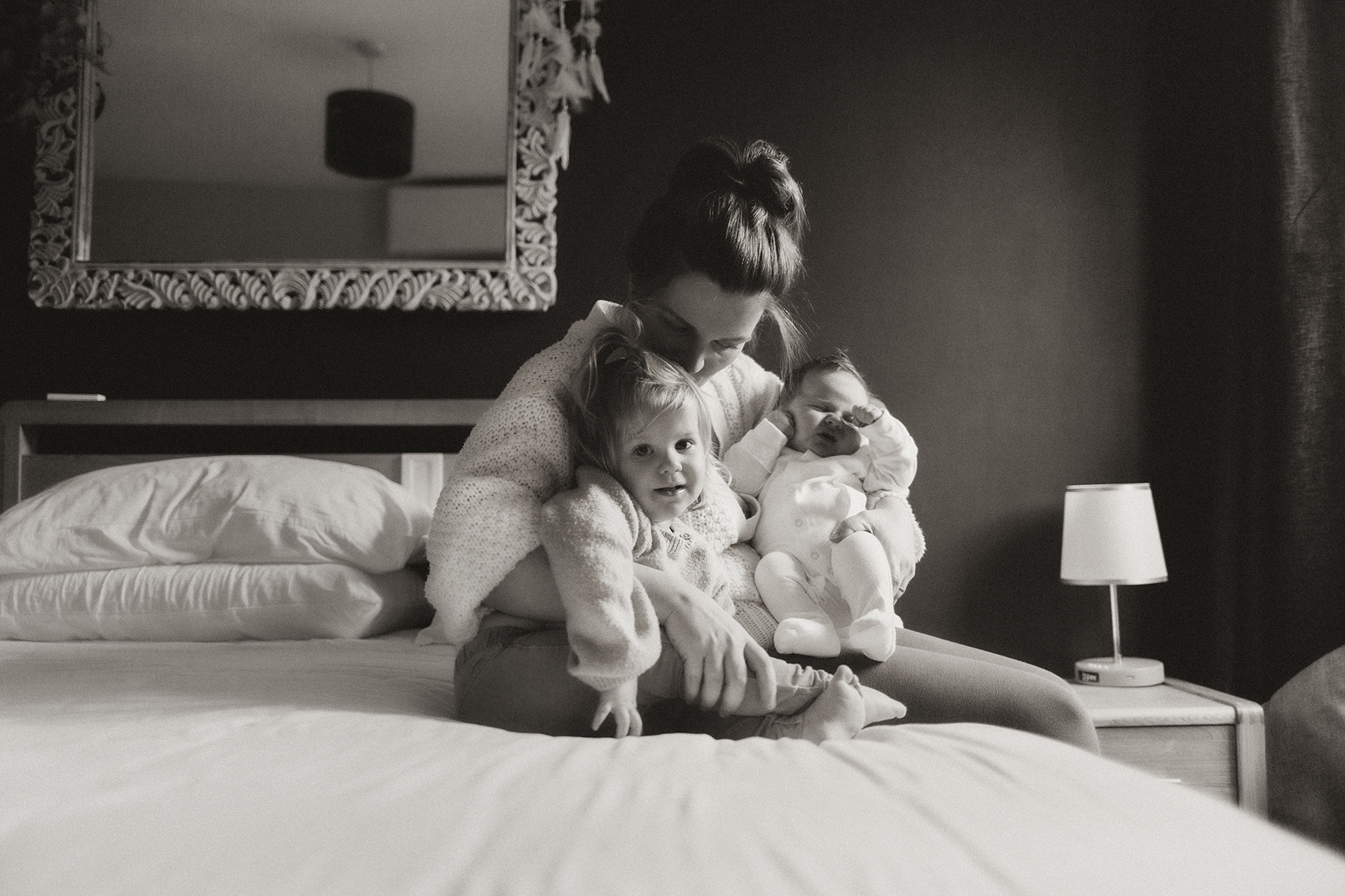 mother cuddling with daughter and newborn