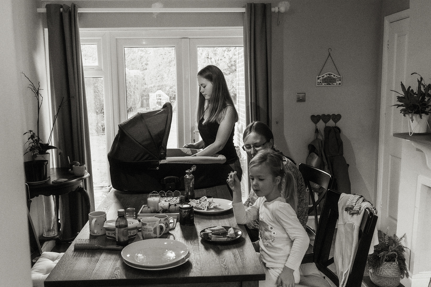 sister looking at baby brother in pushchair