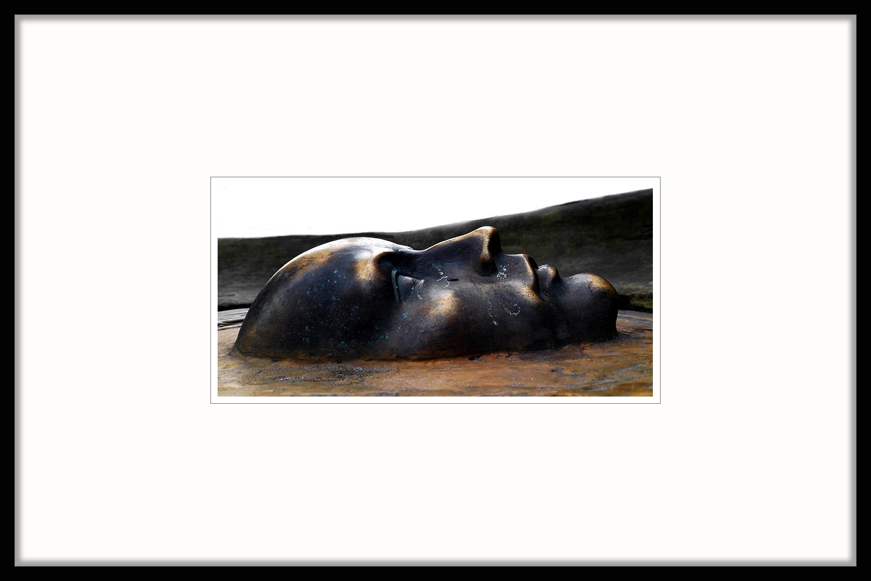 MASKA fotografia 30x14cm; passe-partout; rama alu ......... / Fotografia to część instalacji autorstwa Anny Szalast, która wystawiała swoją pracę w Pasażu Stefana Wiecheckiego "Wiecha". Rzeźba składa się z poziomego kamienia, zatopionej w nim maski wykonanej z brązu oraz stalowego krzesła.