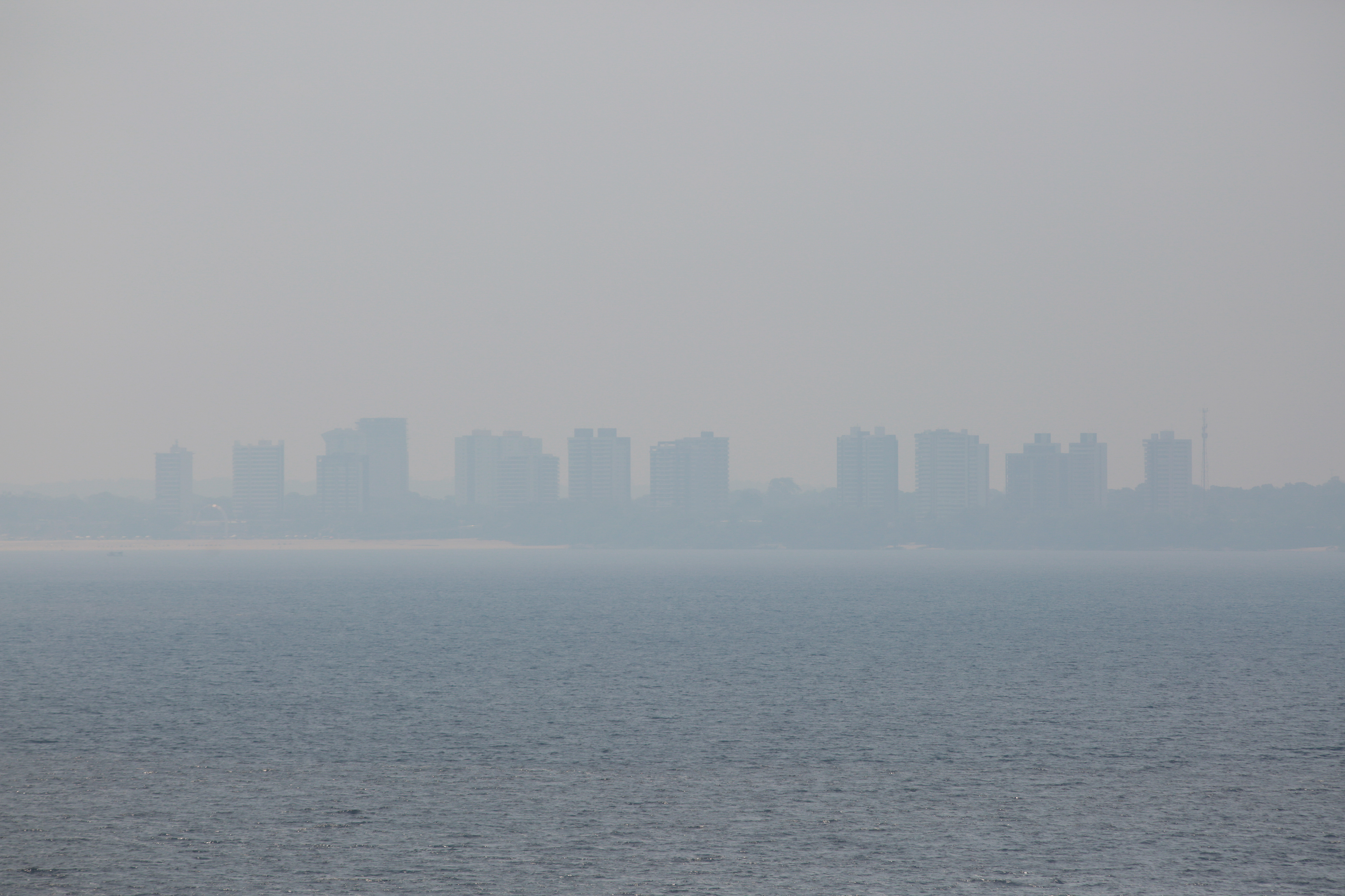 Buildings along the Ponta Negra beachfront covered by a thick layer of smoke in early August 2024. Smoke from Amazonian forest fires in the interior of the state began to invade the capital Manaus, with winds blowing toward the city causing concerns about naval and aerial visibility, health issues, and environmental impact. Photo: AFP/Suamy Beydoun