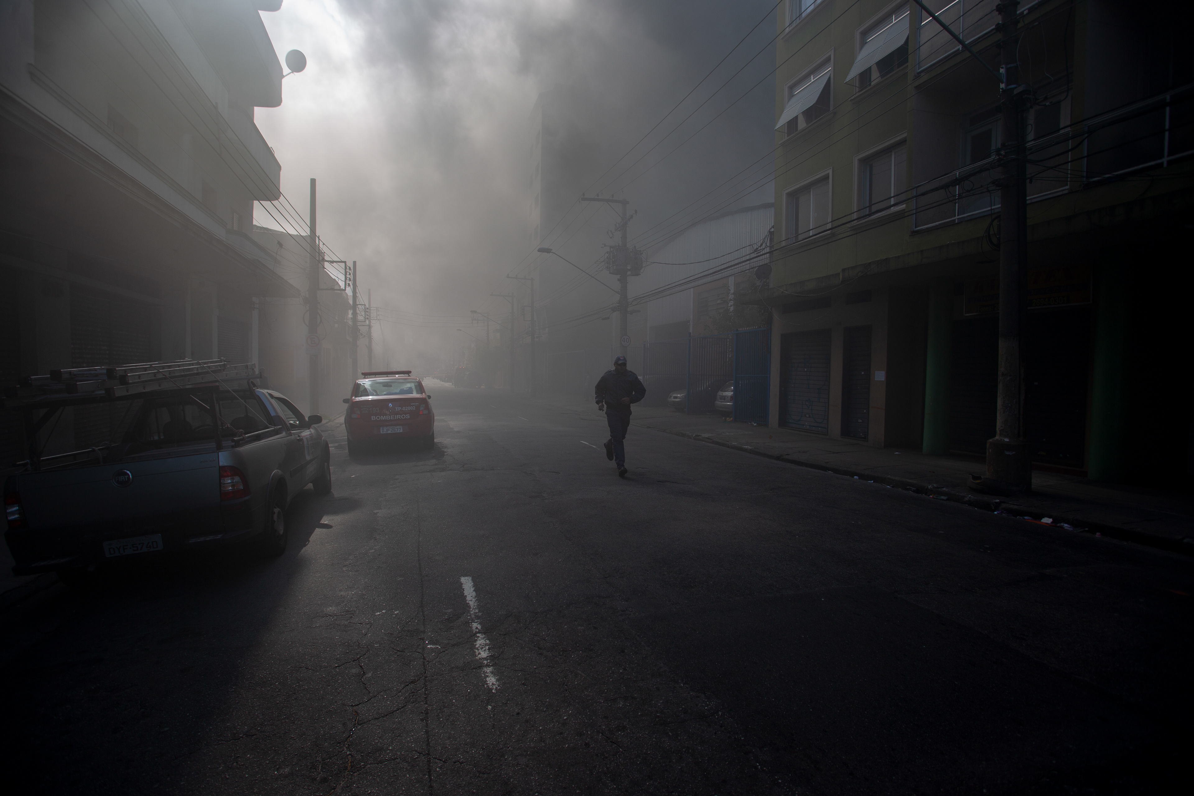A military police officer runs alone down a smoke-filled street during a major fire in the Bresser Mooca neighbourhood of São Paulo in June 2016.  Photo: FP/Suamy Beydoun