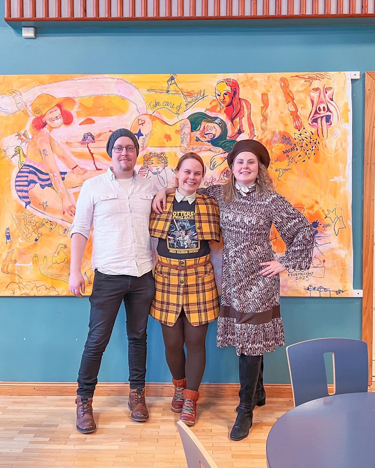 Timo Ahjotuli, Elli Maanpää, and Terese Kühl, radiating joy as they pose beside the donated artwork.