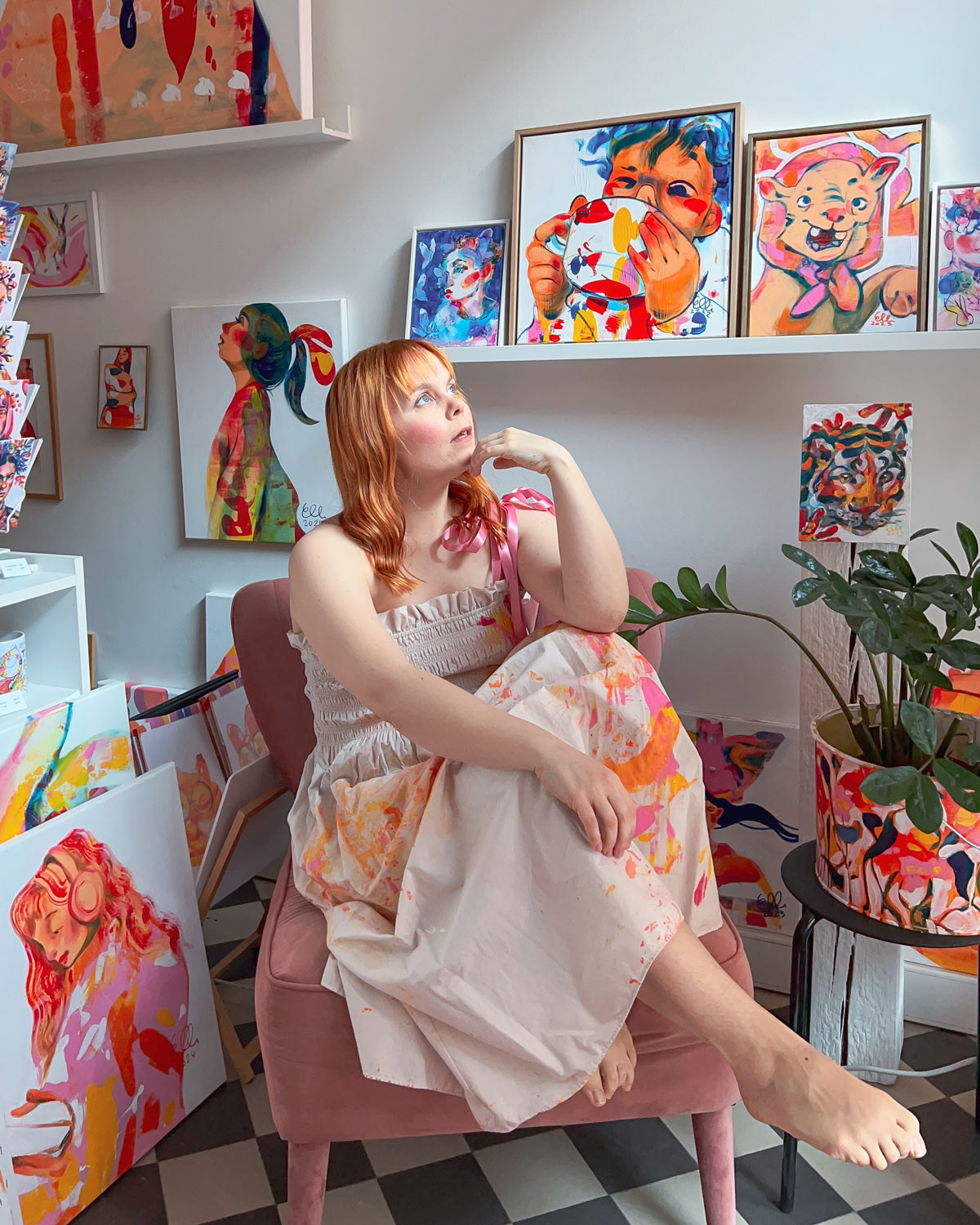 Elli Maanpää in her art studio, surrounded by colorful paintings and creative work-in-progress.