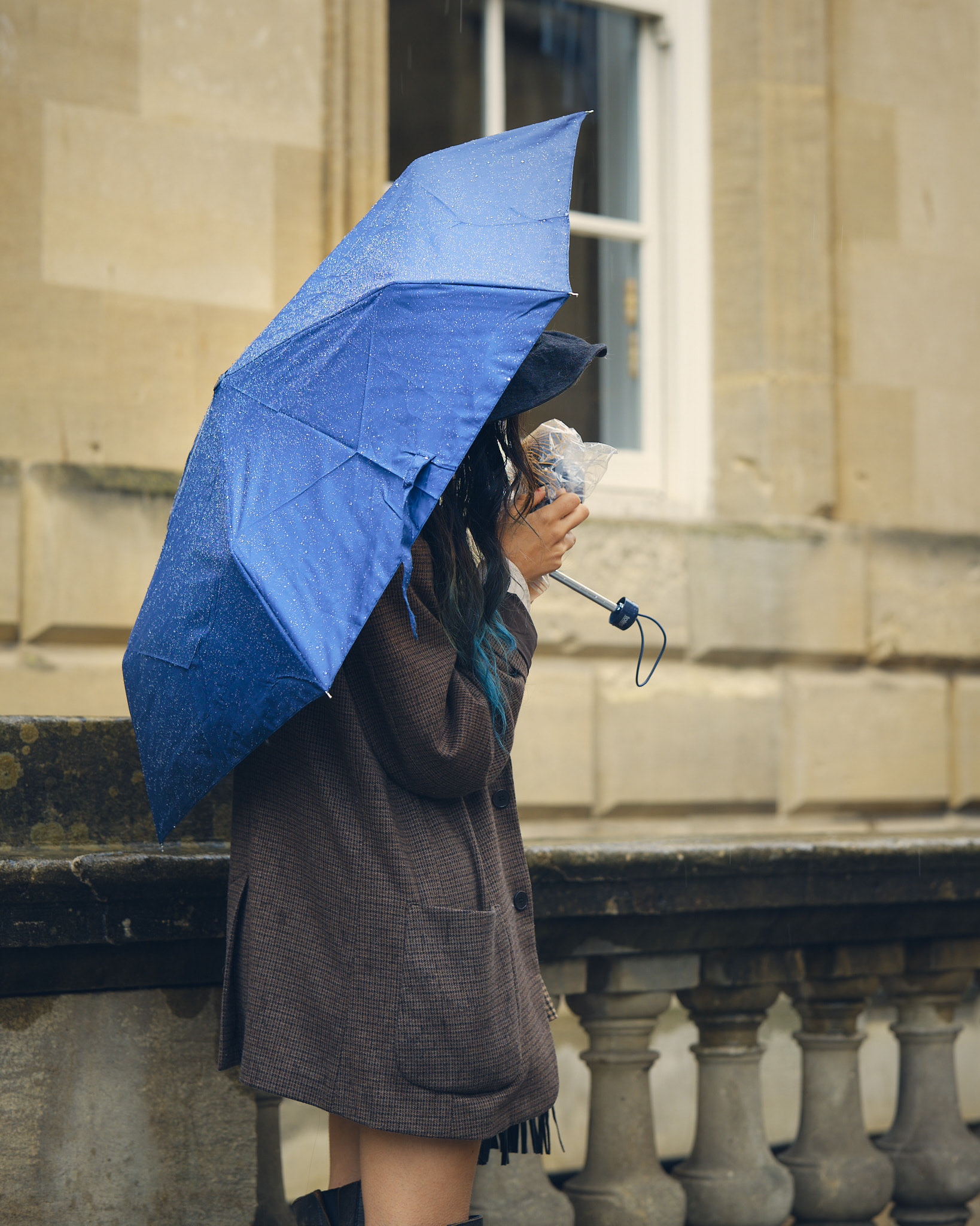Girl with umbrella taking a photograph in the rain