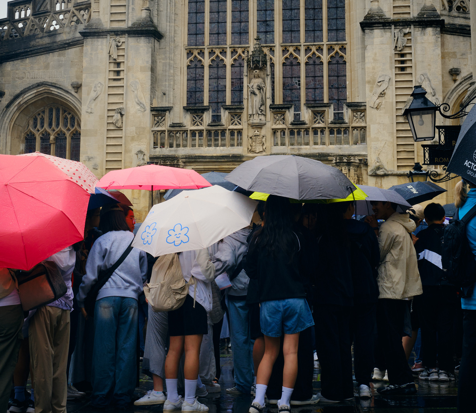 Tourists group together with umbrellas in the rain