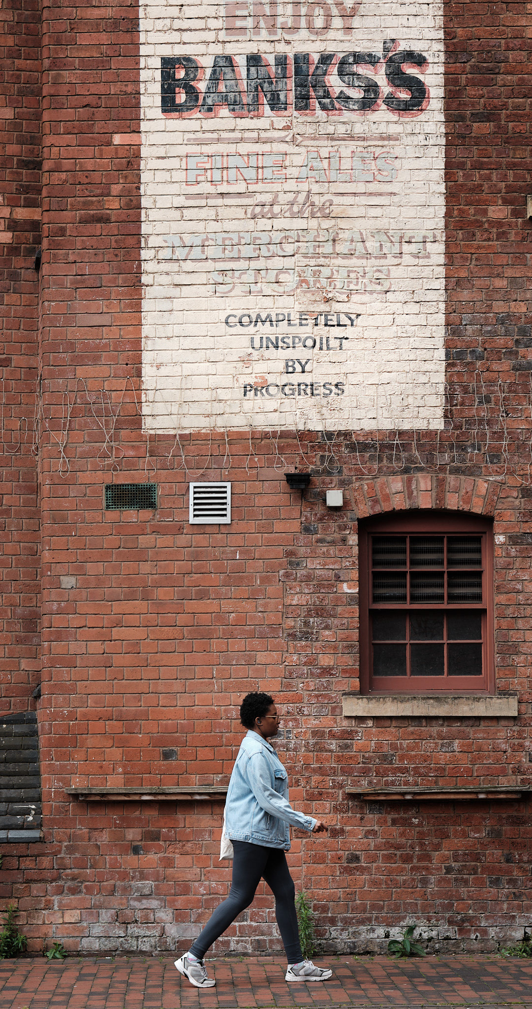 Woman walking past a sign painted on a wall