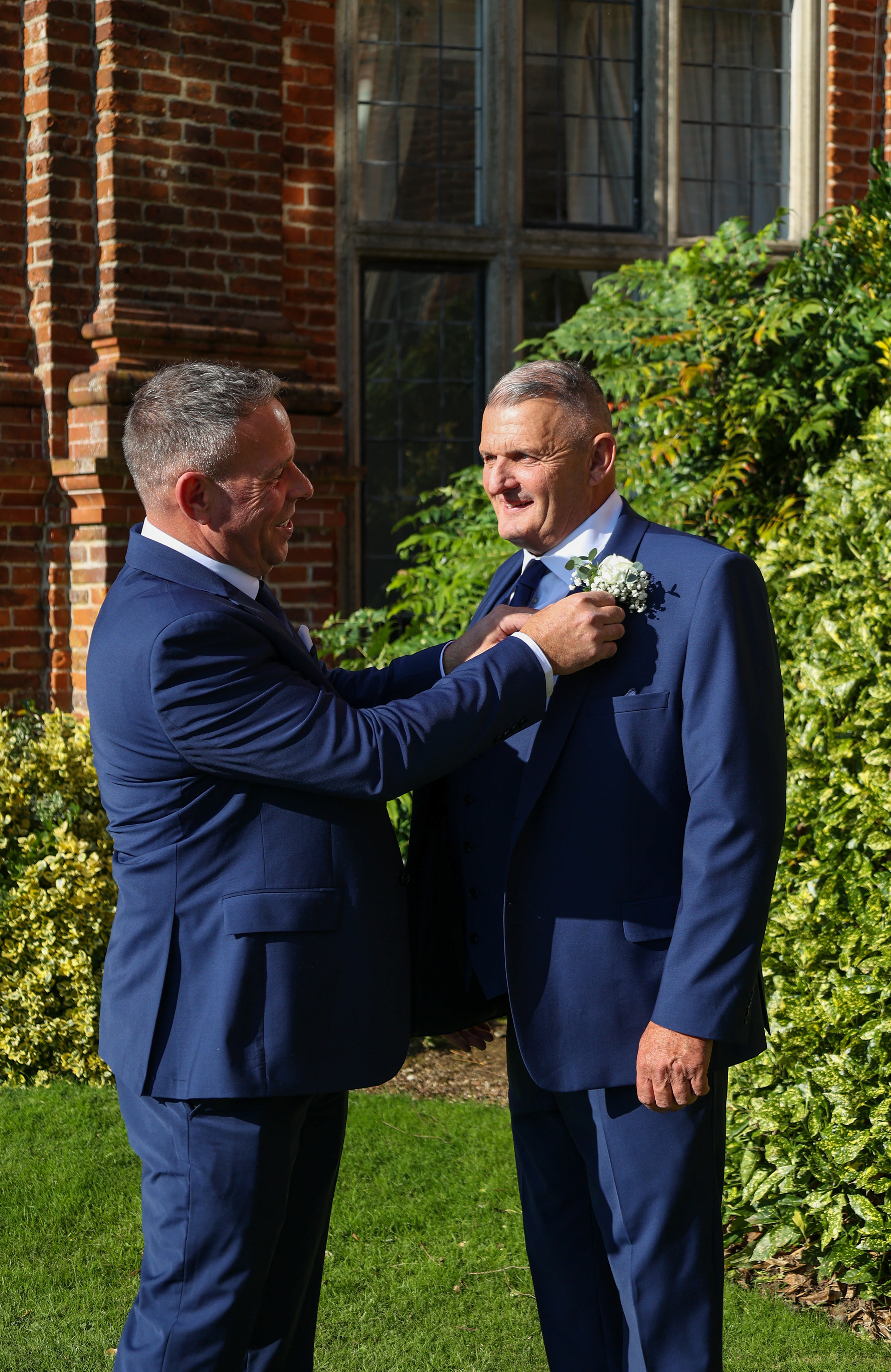 A best man’s final touch: Adjusting the groom’s boutonnière for a picture-perfect wedding moment.