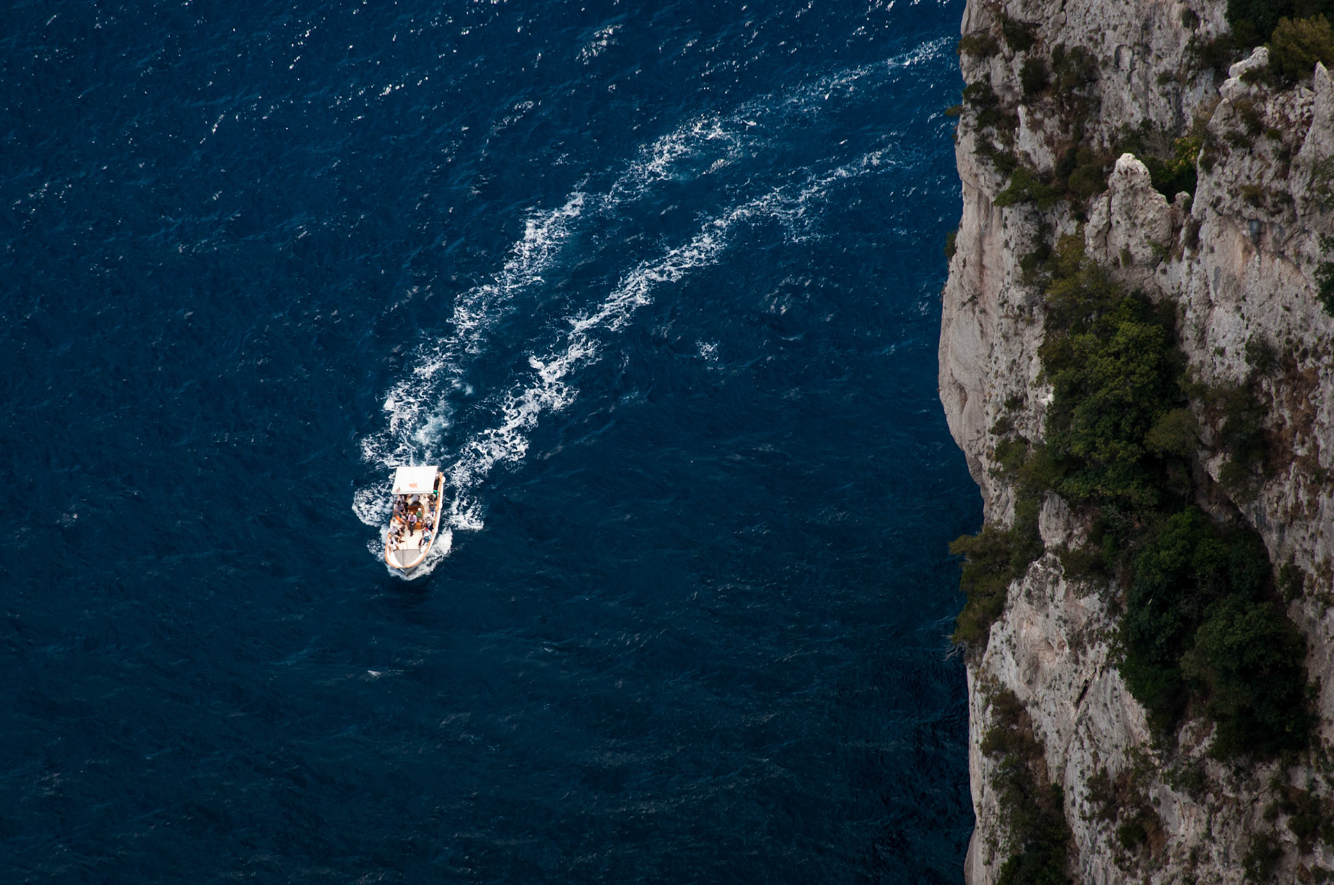 A small boat speeds round the headland on the beautiful island of Capri.