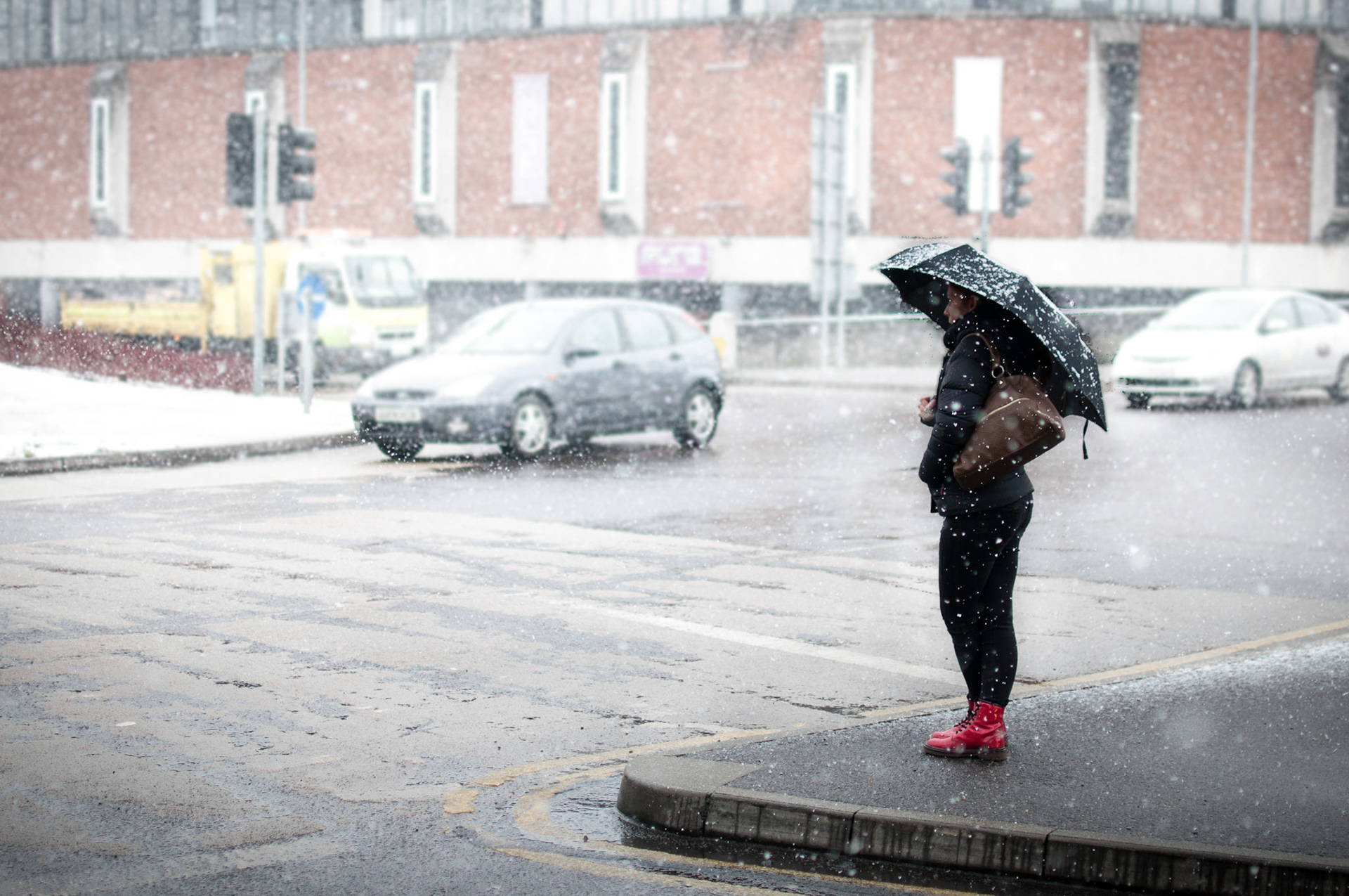 This girl is waiting for a lift while hiding under her brolly.