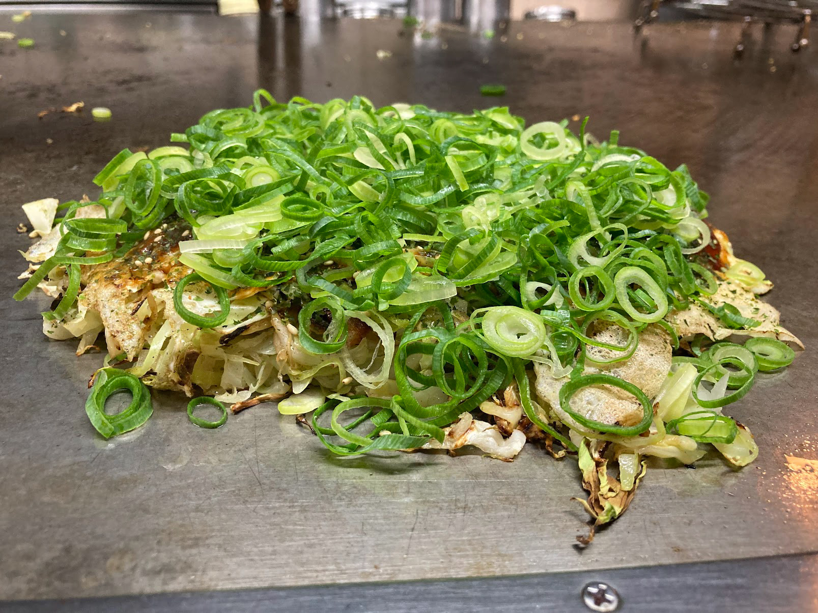 The amazing Hiroshima okonomiyaki...and this was "half sized." Made right in front of me on the teppan grill with such masterful skills. The hiroshima style is a combo of: thin flour crepe, mountain of cut cabbage that will cook via heat, thin strips of pork, thin flour crepe, fried egg, heaps of green onion, with lots of different spices and sauces in between.