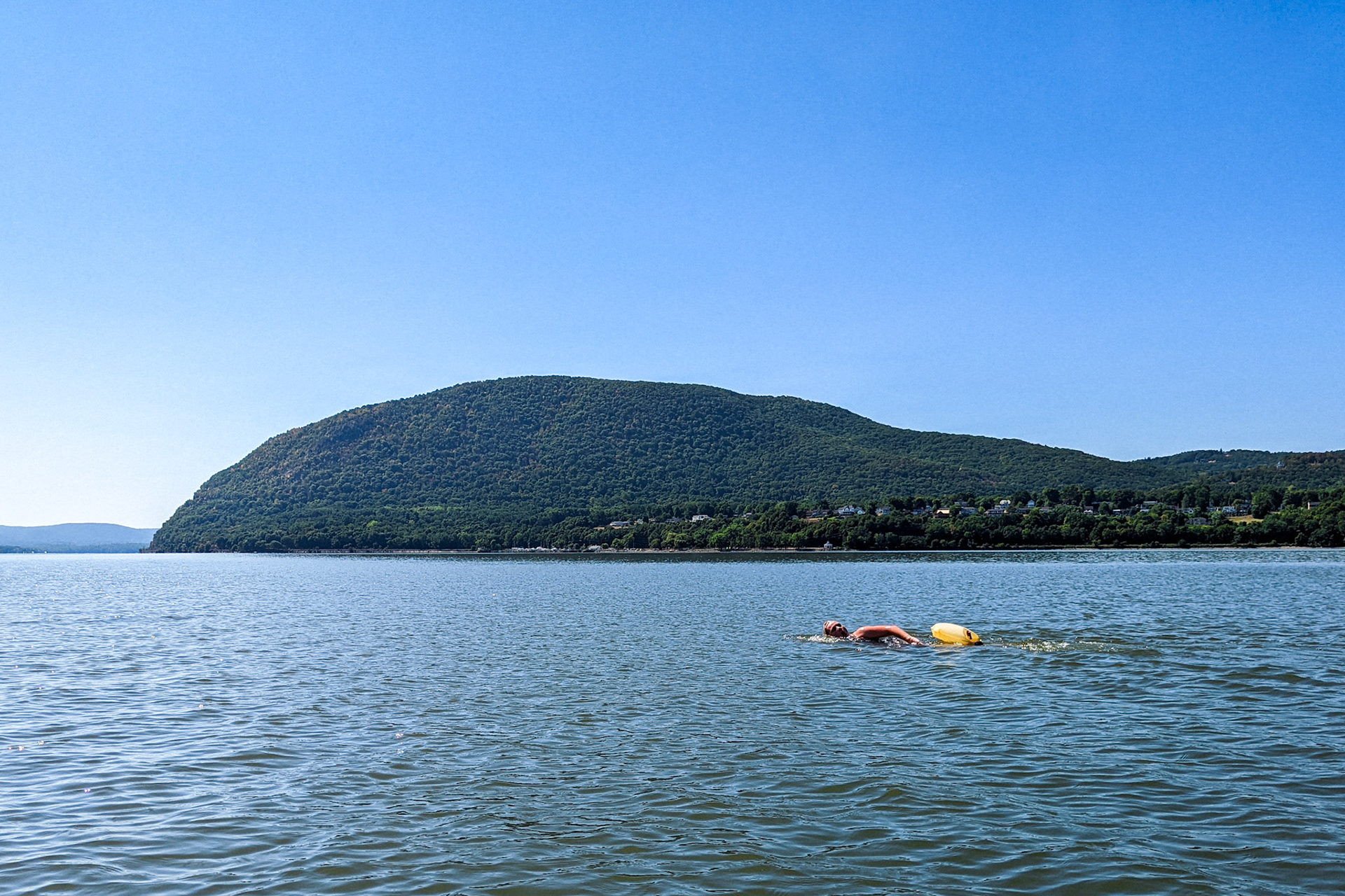 An artist swims across the Hudson River in front of Storm King Mountain