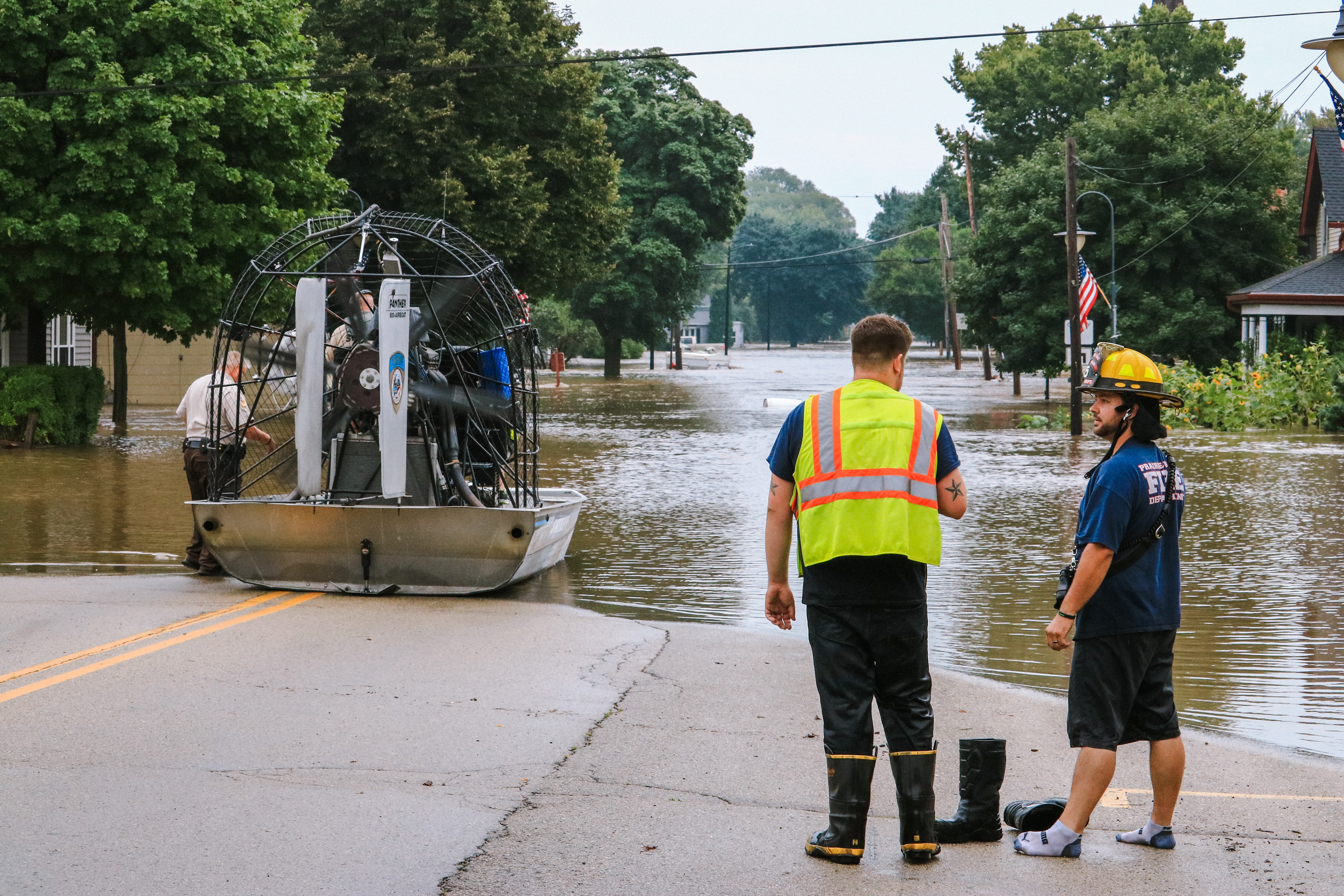 Two firefighters watch the floodwaters on Hudson Street as an air boat gets ready to launch.