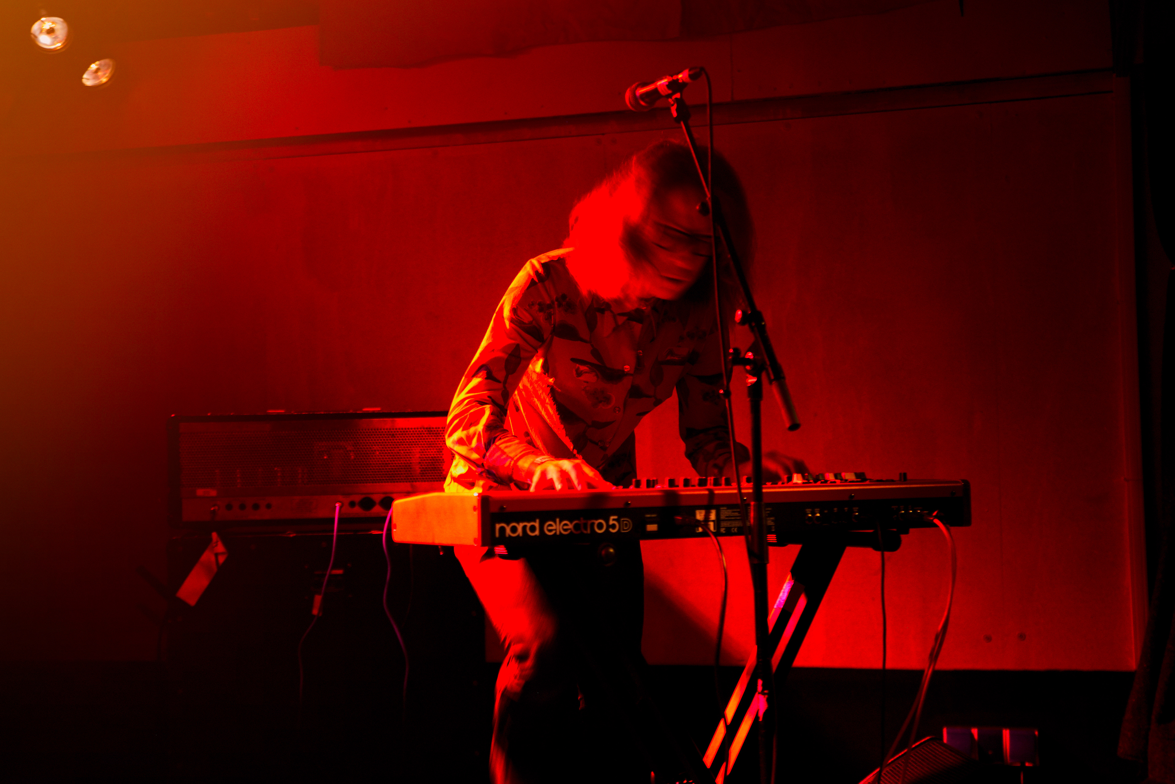 joel sarakula. playing keyboards. very passioned. the room is red lighted