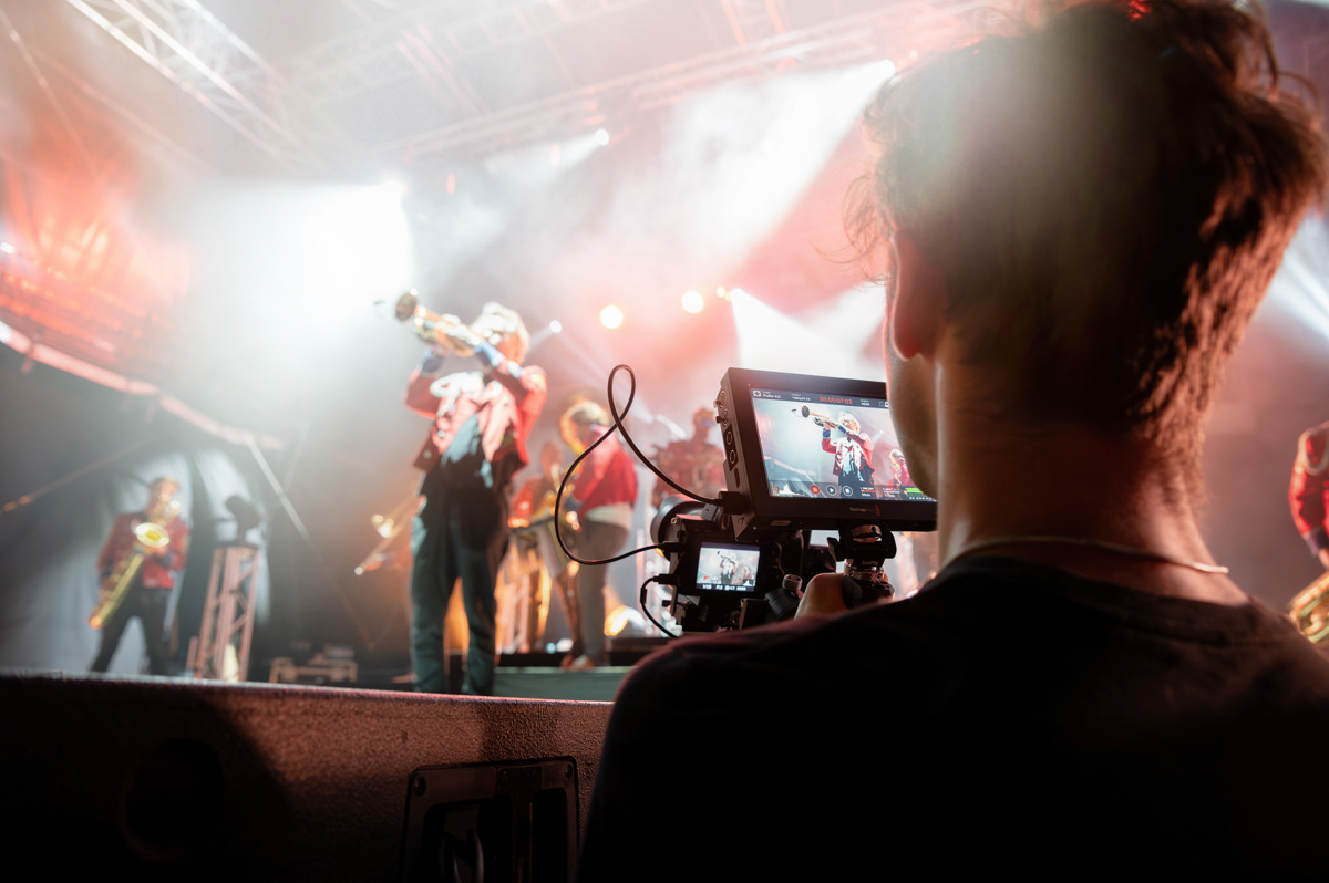 camera man filming a band which is playing on stage
