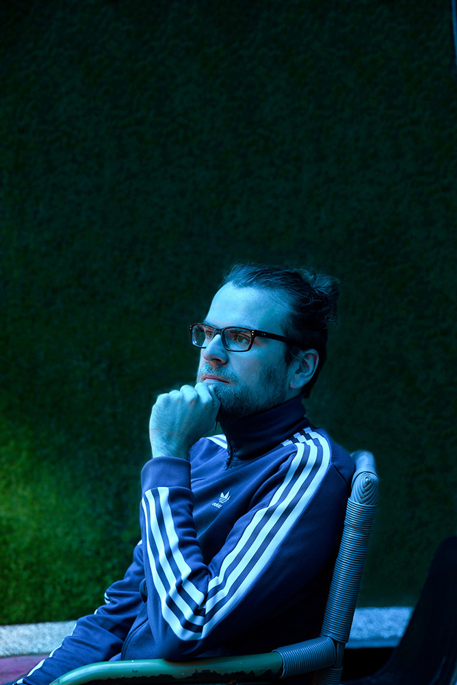 journalist sebastian friedrich seiliches portrait in blauem licht vor wand aus rasen