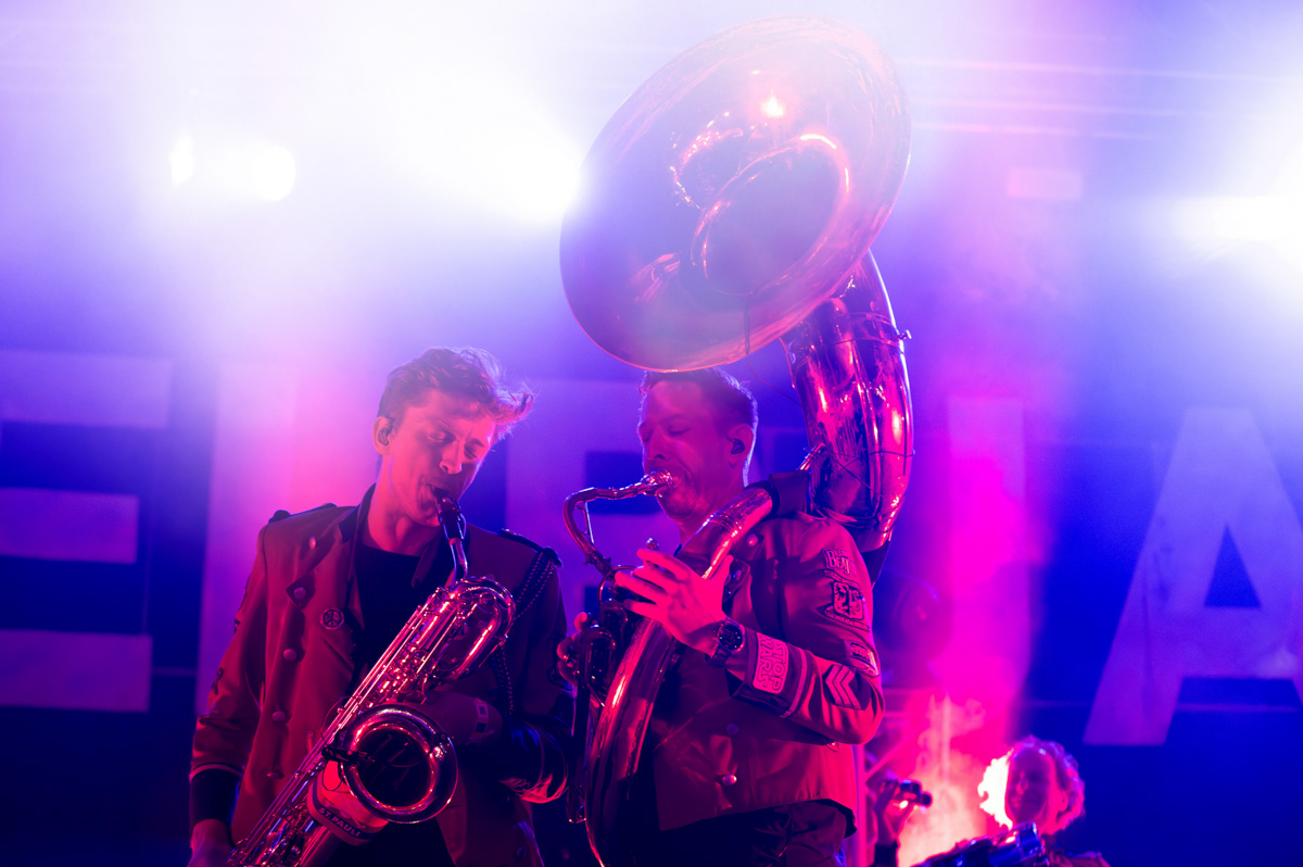 two musicians of meute band playing pn stage. the light is atmospheric pinnk and blue