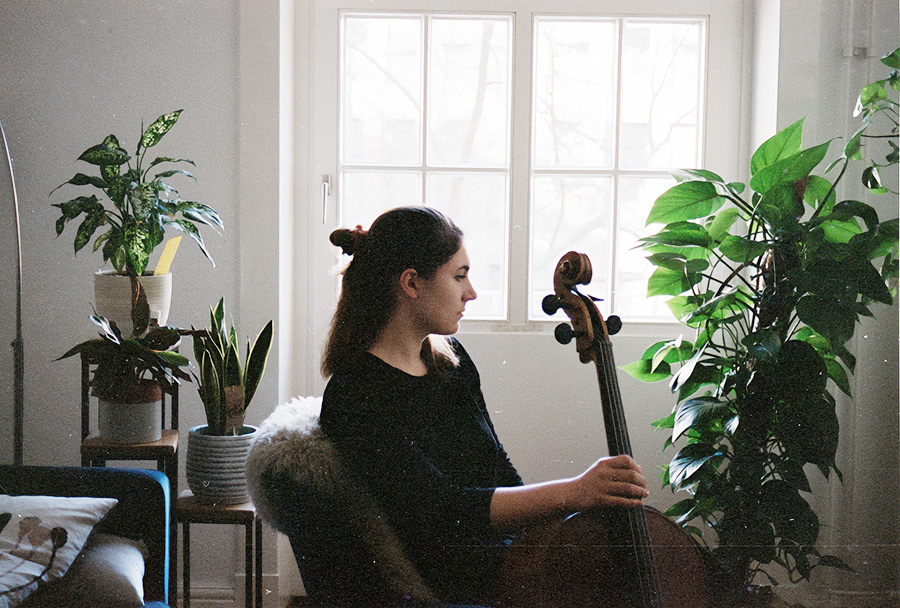 seitliche fotografie musikern sitzt nachdenklich vor einem fenster , und hält ein cello