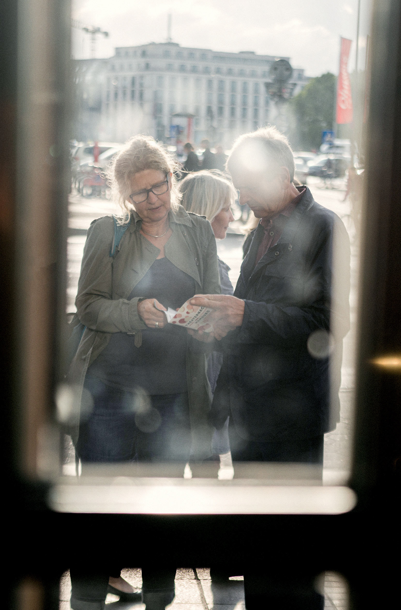 2 personen hinter einer glastür, die ein gedrucktes program studieren