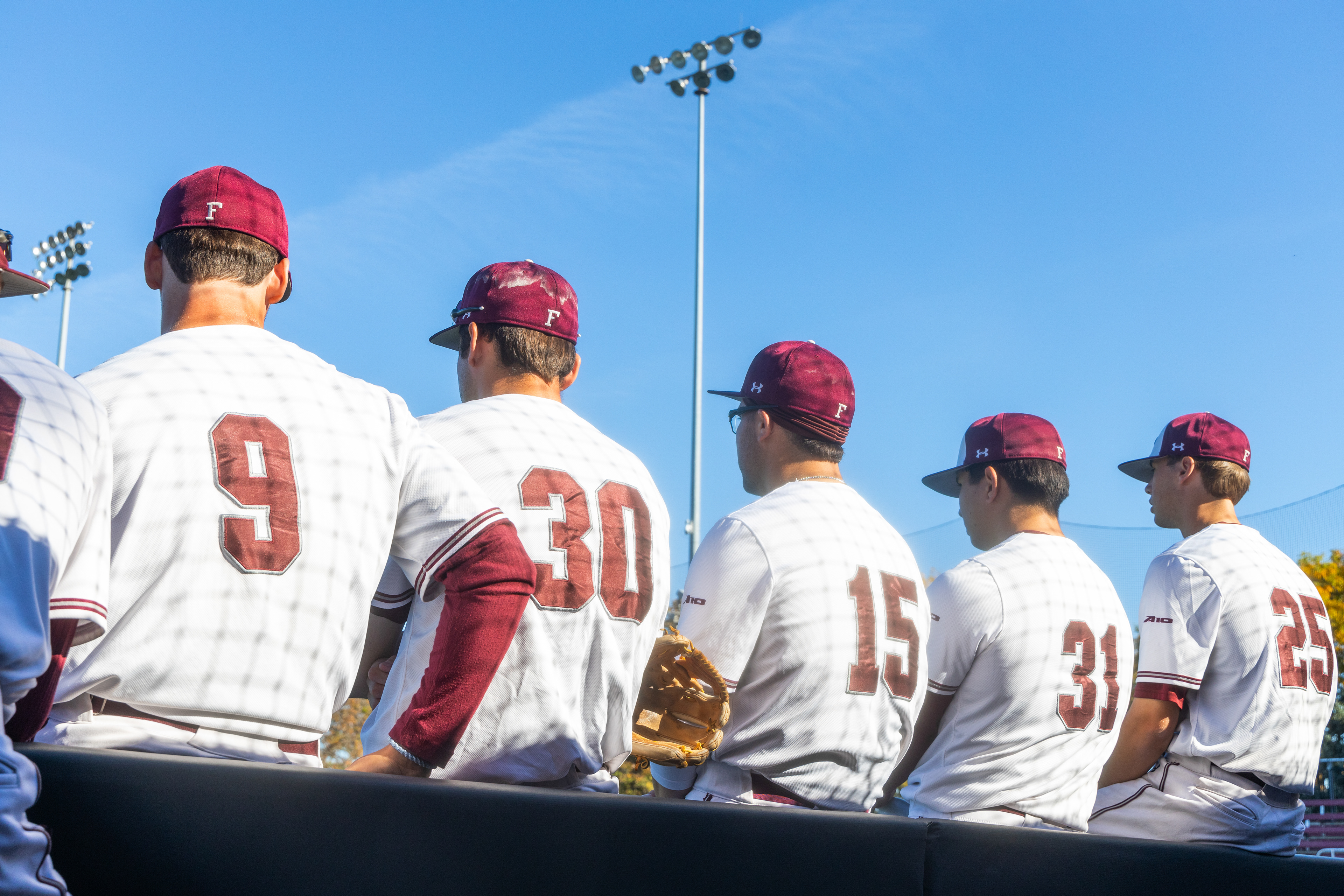 Players watch the game unfold in front of the dugout.