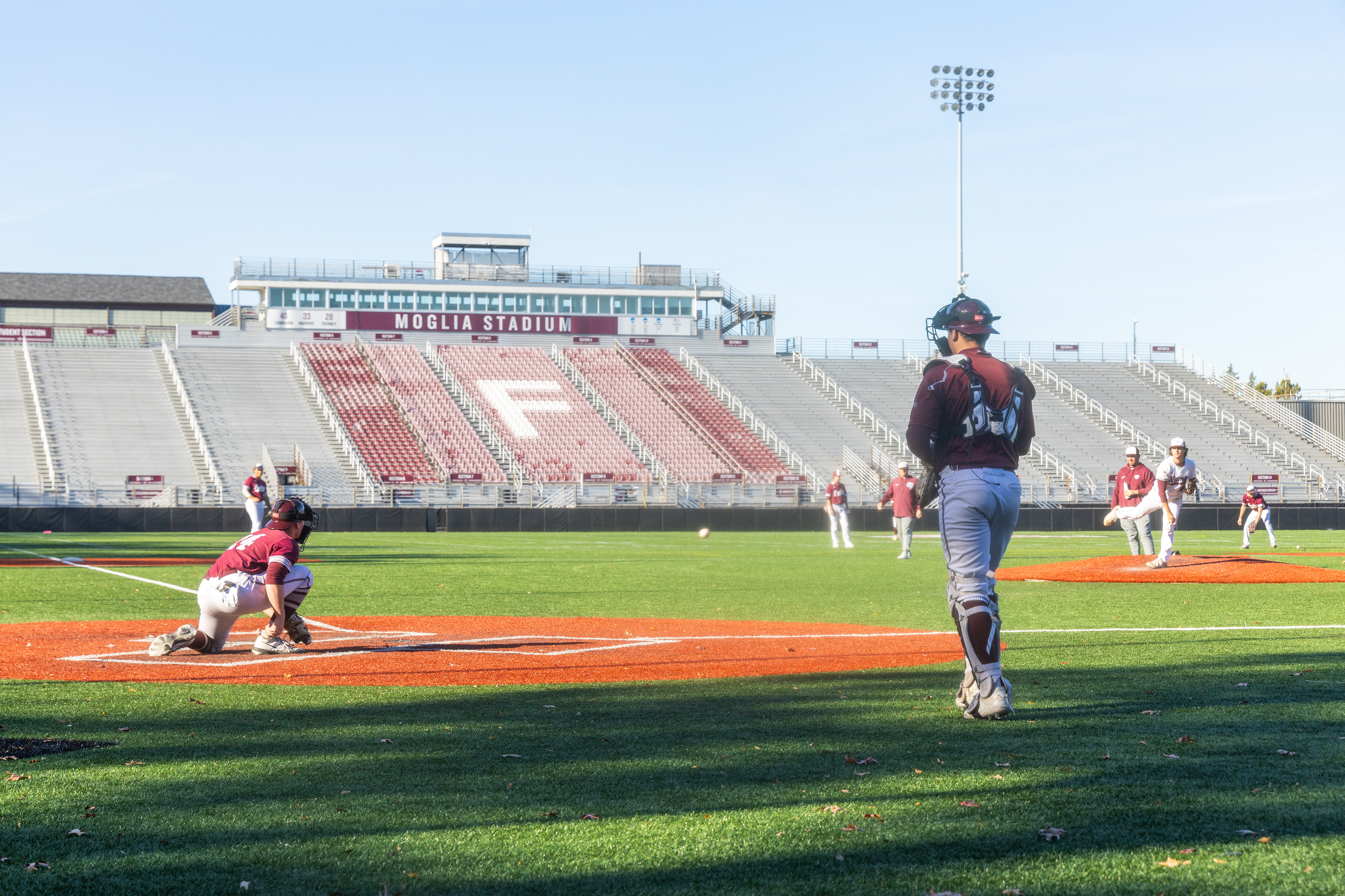 A catcher (right) arrives on field to replace the catcher (left) after the inning is over to promote equal practice times for all team catchers.