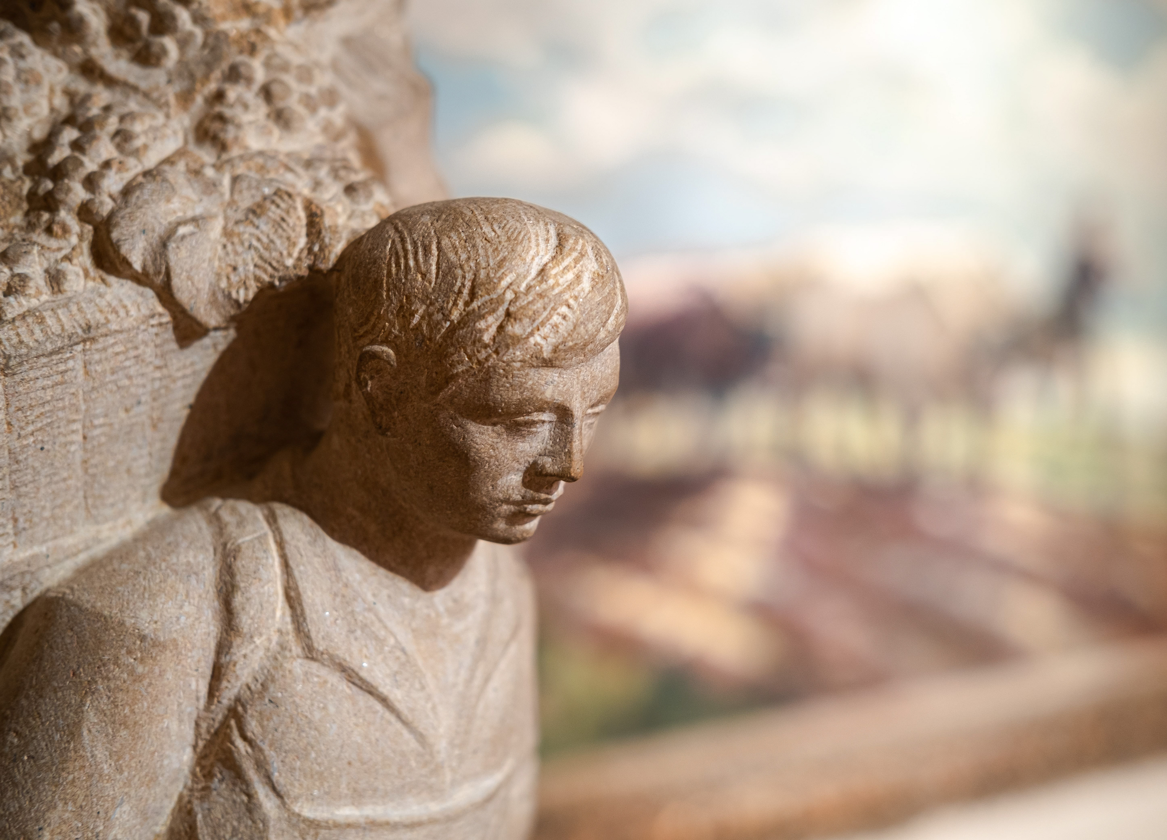 Statue en pierre d'un jeune homme au musée des Ursulines à Mâcon : Statue finement sculptée devant un tableau bucolique. Lumière douce mettant en évidence les détails et la texture de la pierre. Photographie par Etienne Gatheron, expert en patrimoine culturel.