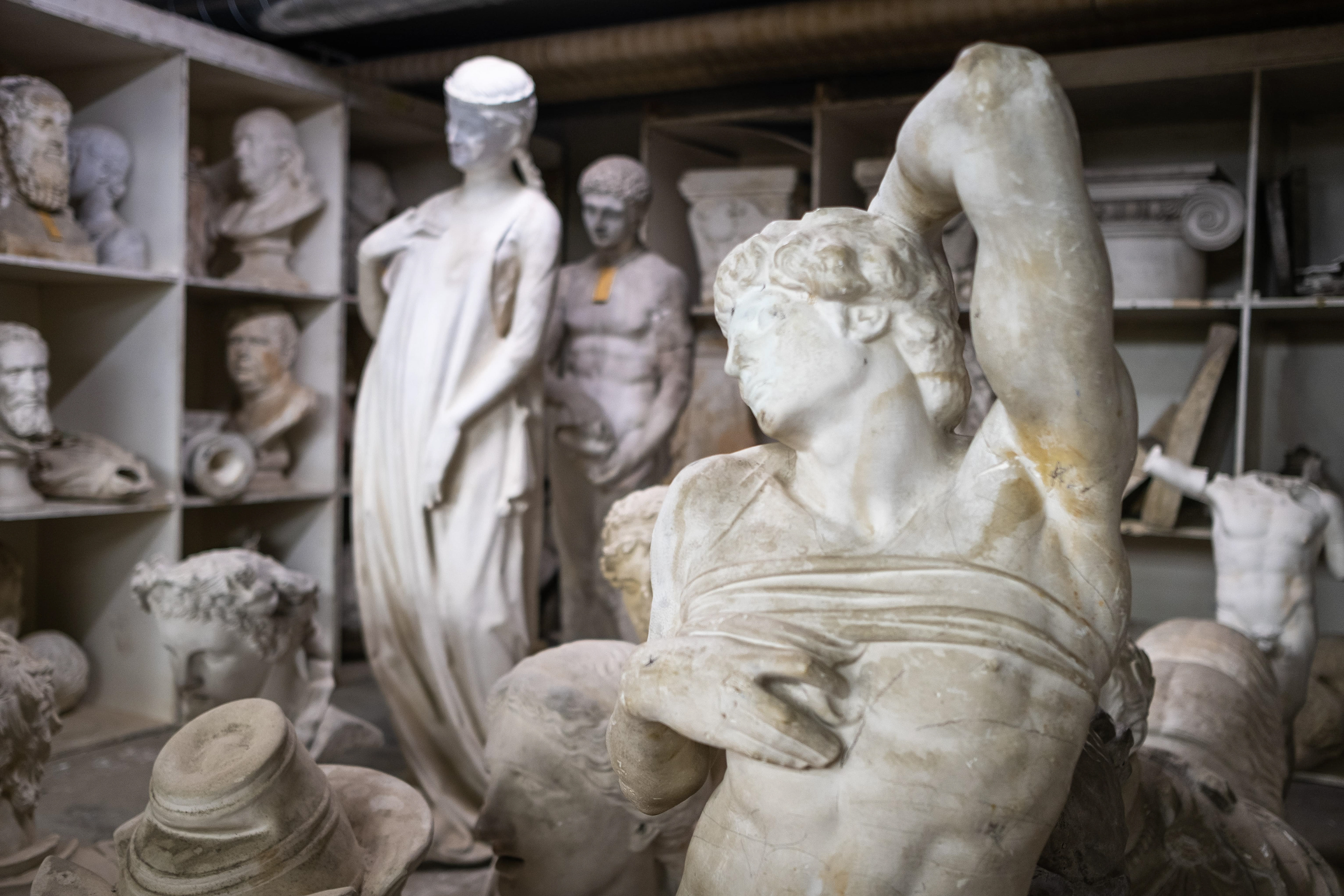 Atelier rempli de moulages de statues à l'École Municipale d'Arts Plastiques (EMAP) de Mâcon : Atelier avec bustes et figures humaines, reproductions d'œuvres classiques et modernes, à des fins éducatives et artistiques. Atmosphère de sanctuaire de l'art. Photographie par Etienne Gatheron, spécialiste des sites artistiques.