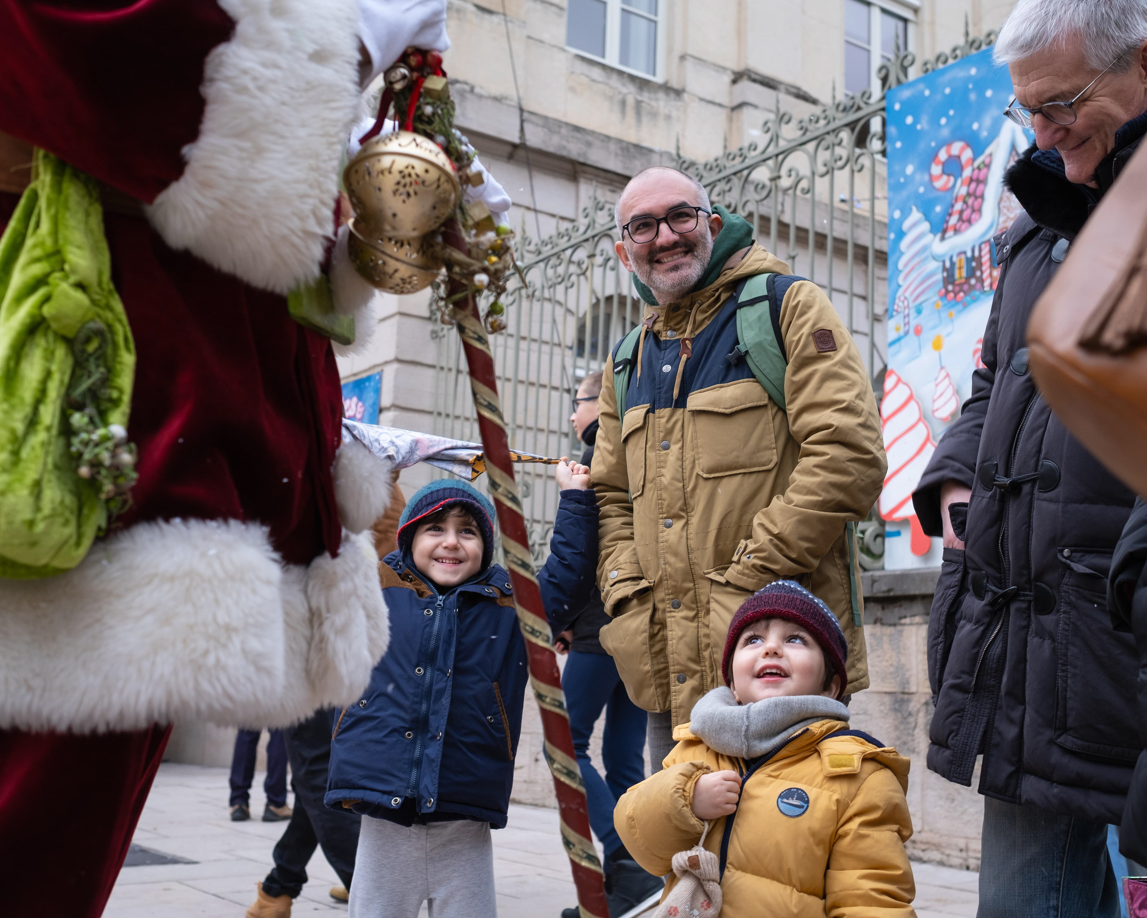 Enfants souriants rencontrant le Père Noël lors d'un événement festif à Mâcon, Saône-et-Loire, Bourgogne, Rhône-Alpes, avec des décorations de Noël en arrière-plan. Photographie capturée par Etienne Gatheron. Photographie institutionnelle.