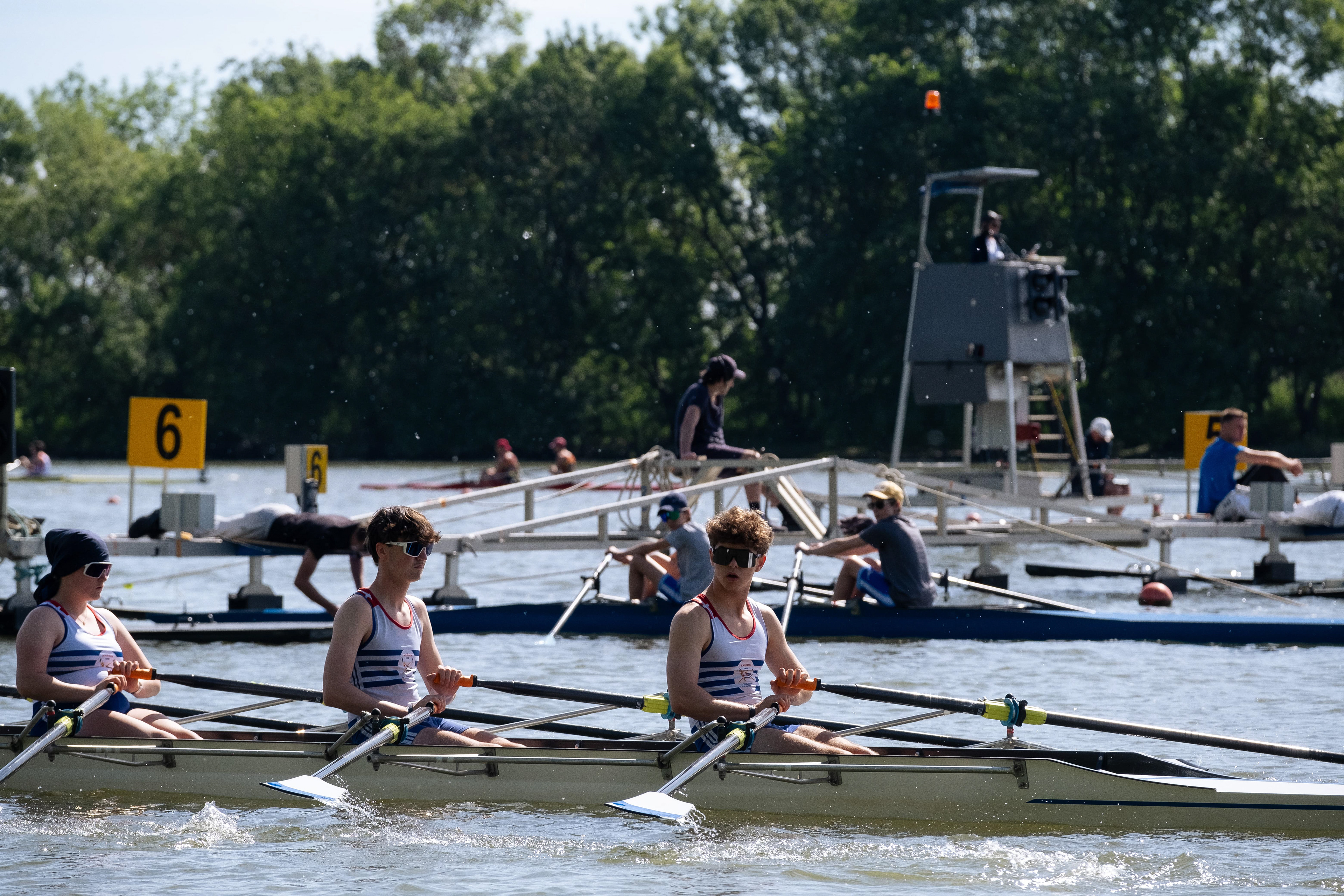 Équipe d'aviron en pleine compétition sur la Saône à Mâcon, Saône-et-Loire, Bourgogne, Rhône-Alpes, avec des rameurs concentrés et des bateaux en arrière-plan. Photographie capturée par Etienne Gatheron. Photographie institutionnelle.