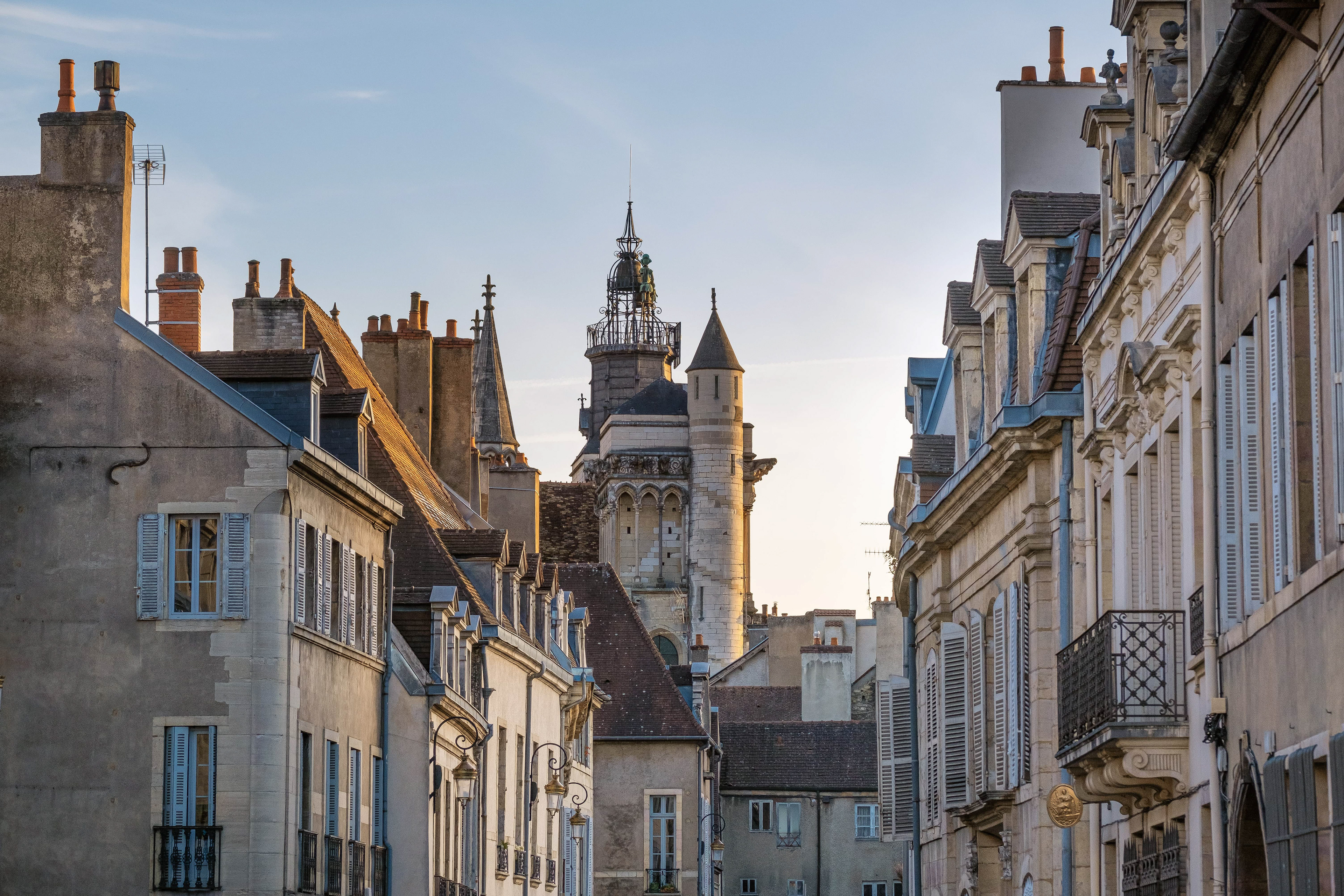 Architecture gothique de l'Église Notre-Dame à Dijon, Bourgogne, entourée de bâtiments historiques sous ciel bleu. Patrimoine architectural et attrait touristique de Dijon. Photographie touristique par Etienne Gatheron.