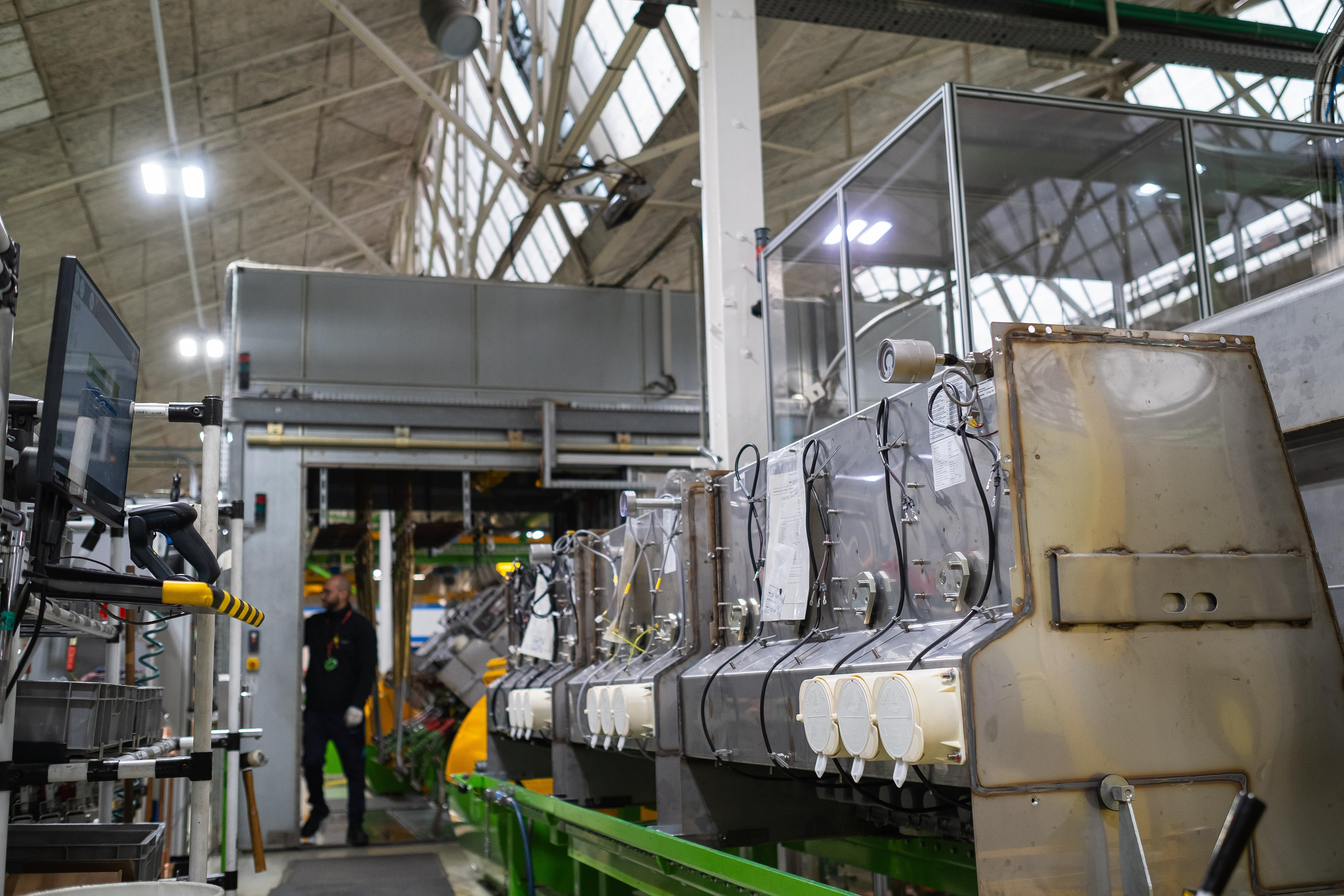 L'intérieur d'une usine moderne en Saône-et-Loire, Bourgogne, Rhône-Alpes, montrant une ligne de production industrielle avec des machines sophistiquées et un ouvrier en arrière-plan. Photographie capturée par Etienne Gatheron. Photographie institutionnelle.